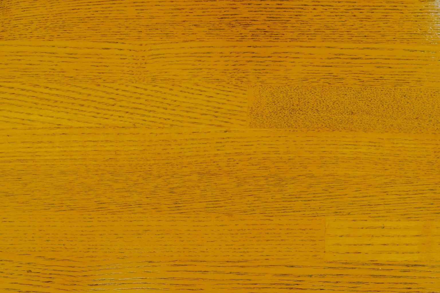 Permukaan kayu kuning cerah dengan serat kayu yang terlihat