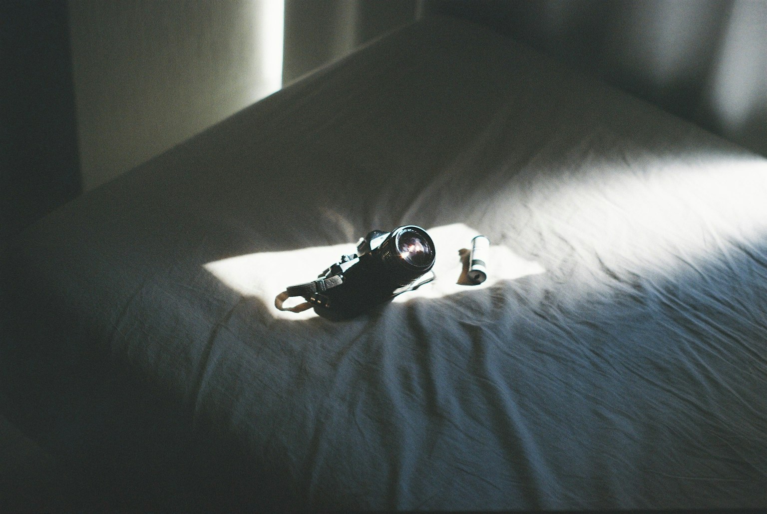 Una zapatilla negra y pequeños objetos iluminados sobre una cama