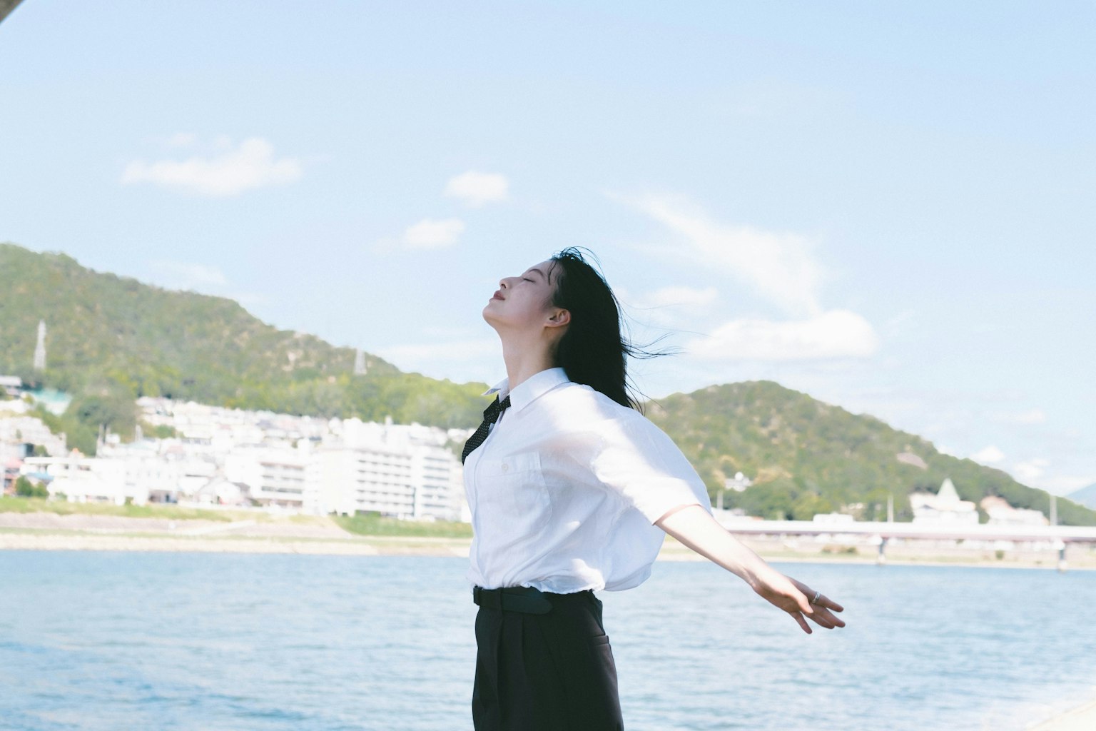 Woman standing by the sea with arms outstretched