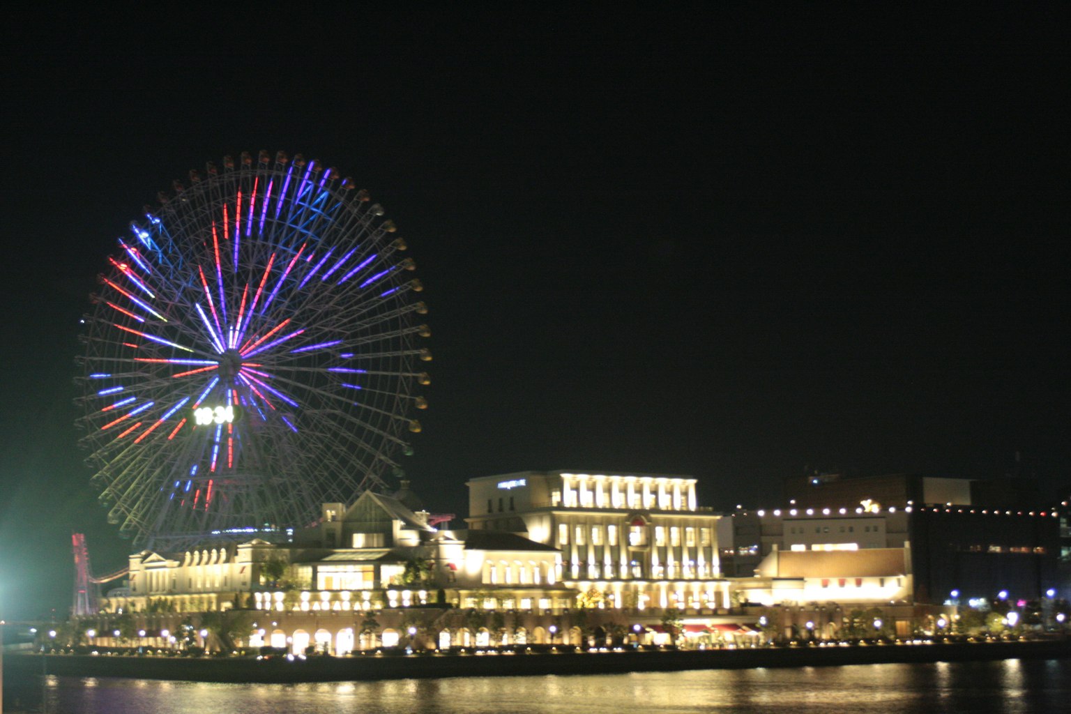 Vista nocturna de una noria y edificios iluminados