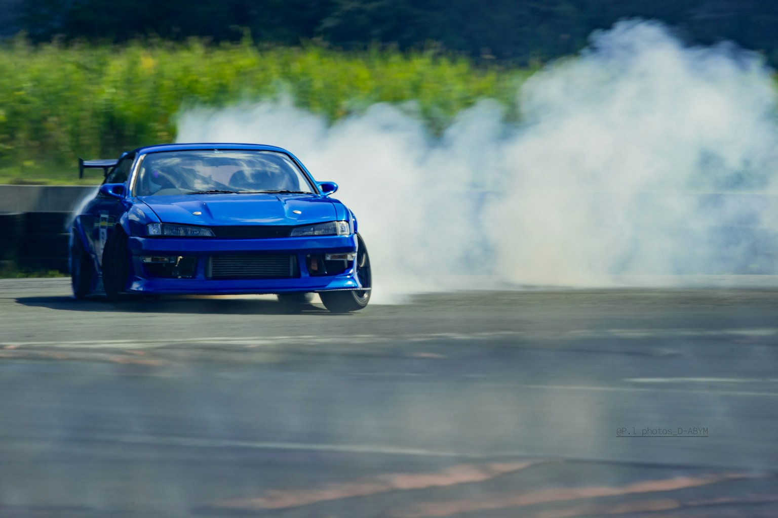 Ein blauer Sportwagen driftet mit Rauch auf einer Rennstrecke