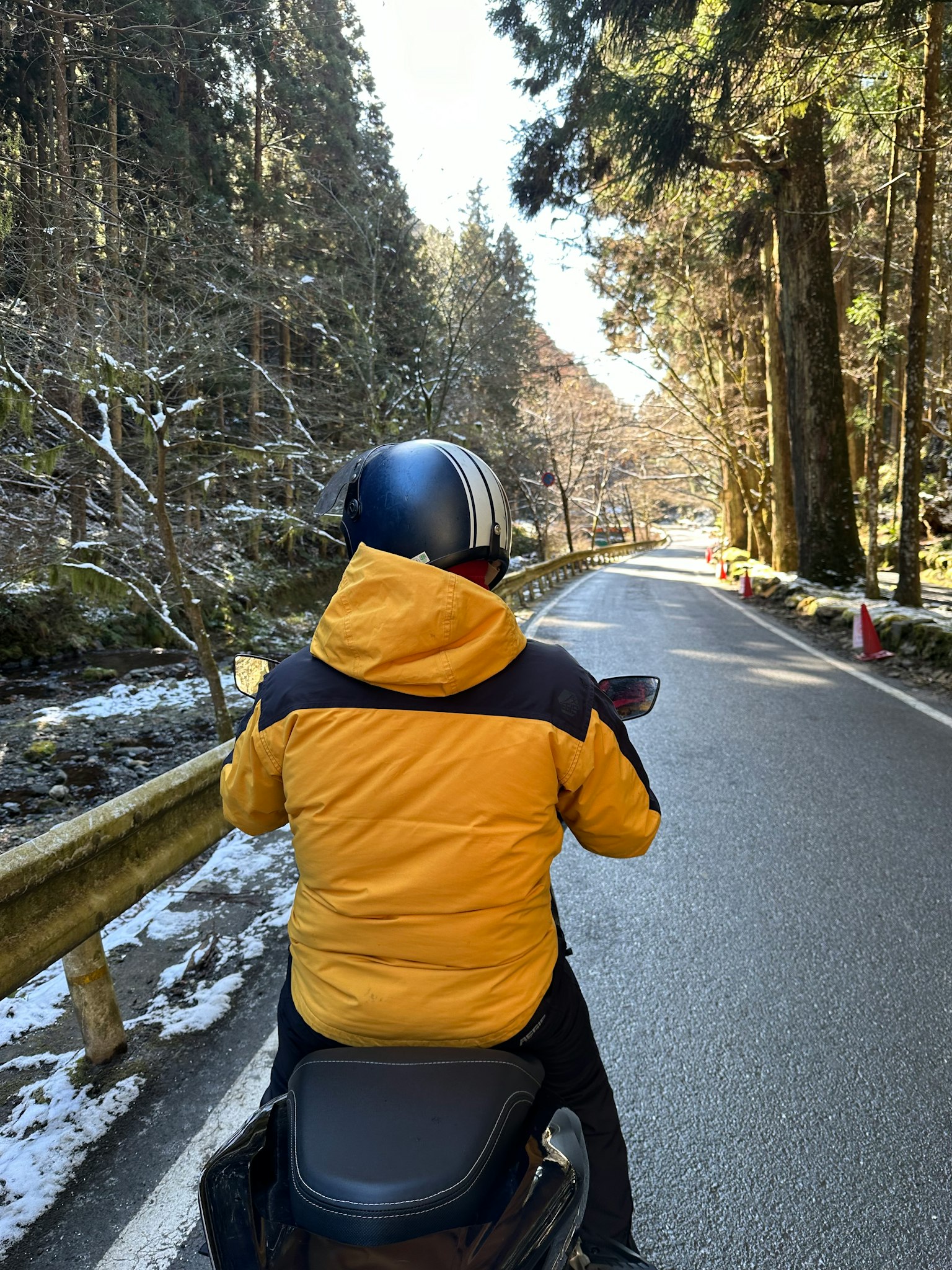 穿着黄色夹克和头盔的人骑着摩托车在雪-covered森林道路上