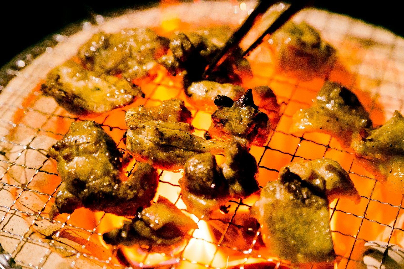 Pezzetti di carne grigliati su una griglia a carbone con le bacchette