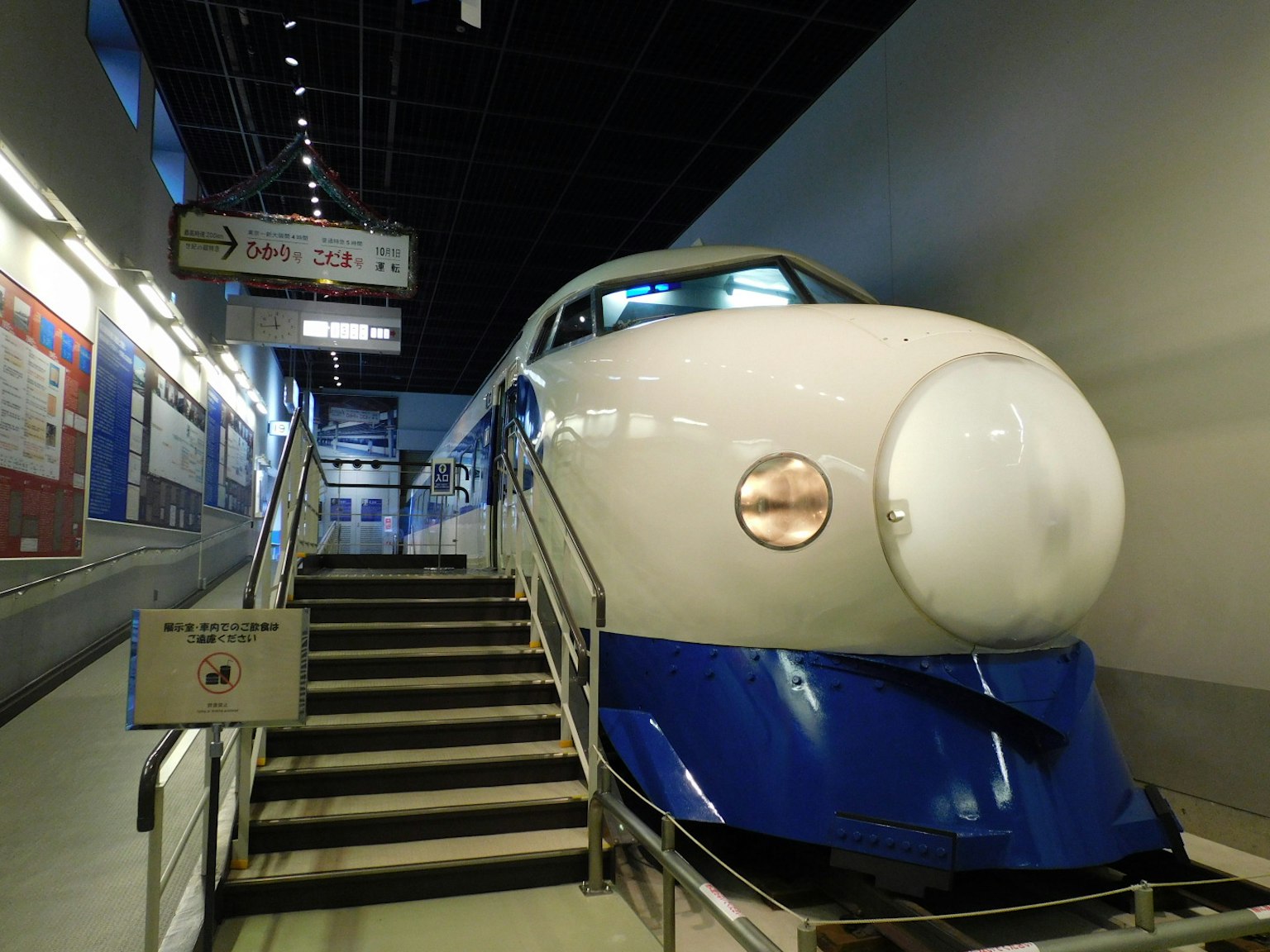 Triển lãm Shinkansen với tàu có hình khí động học màu trắng và xanh gần cầu thang