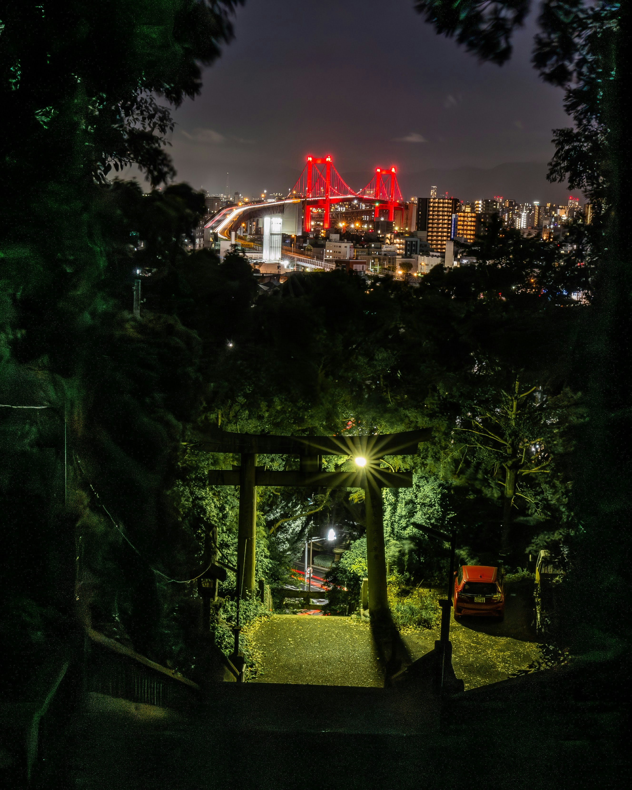 vue nocturne d’une usine avec des cheminées éclairées en rouge à travers les arbres