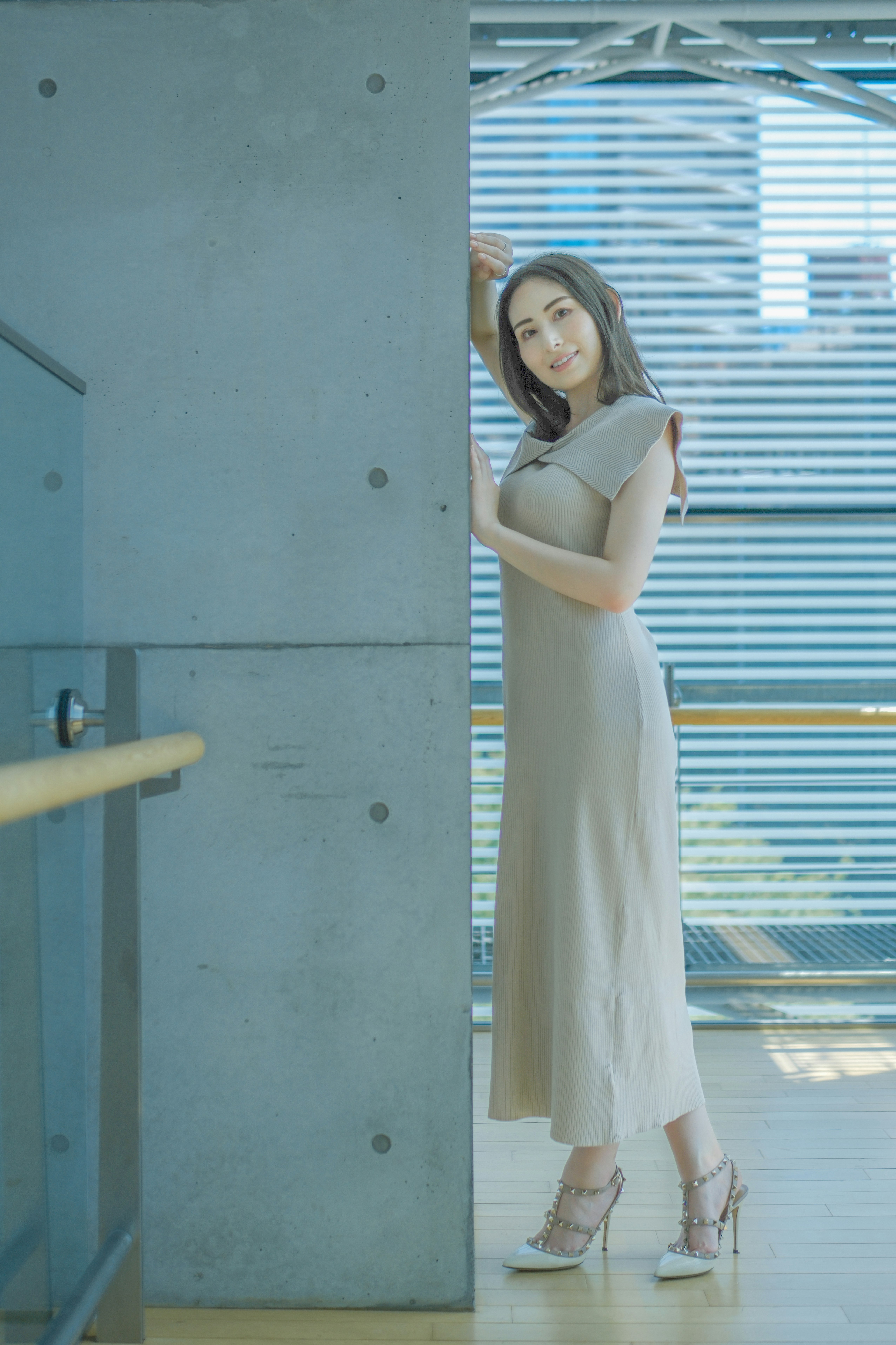 白いドレスの女性が室内の柱のそばで微笑む