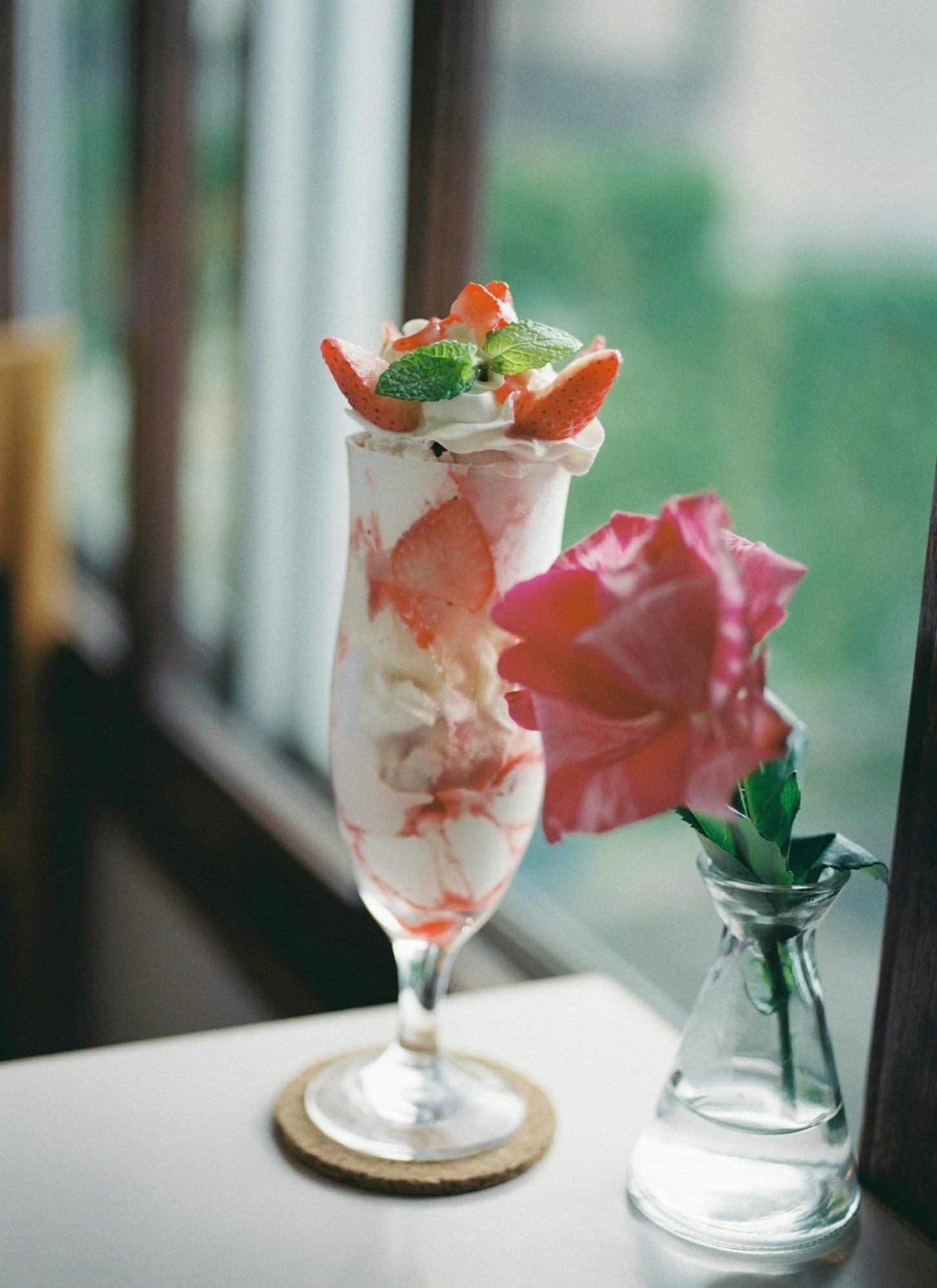 parfait di frutta in un bicchiere con fiori rosa su un tavolo