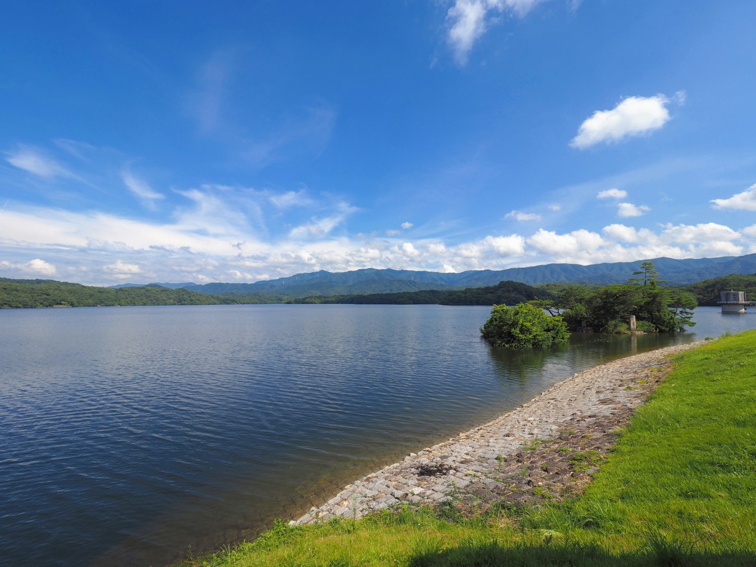 Vista panoramica di un lago con cielo blu e erba verde