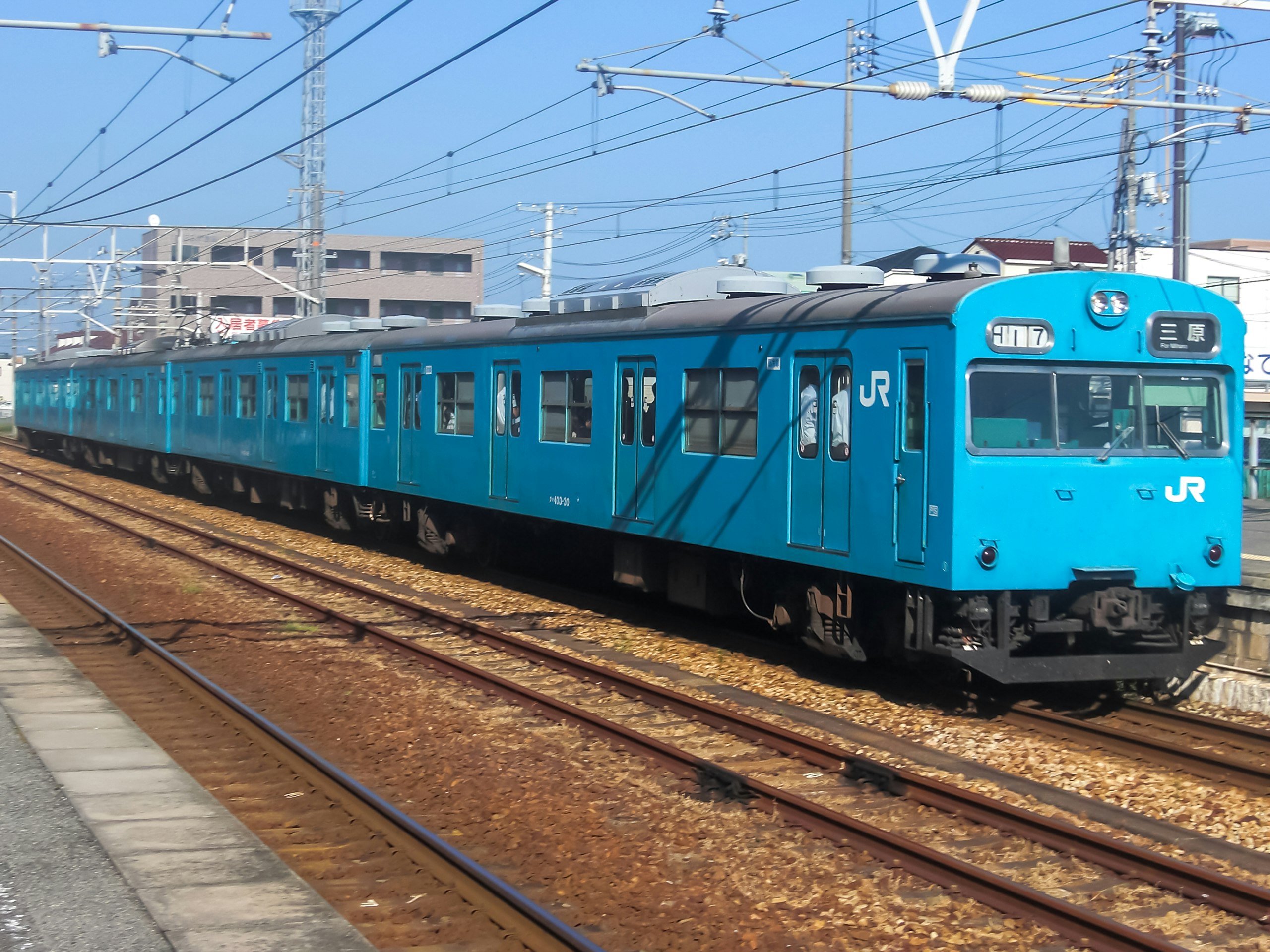 藍色JR列車行駛於車站月台的鐵軌上