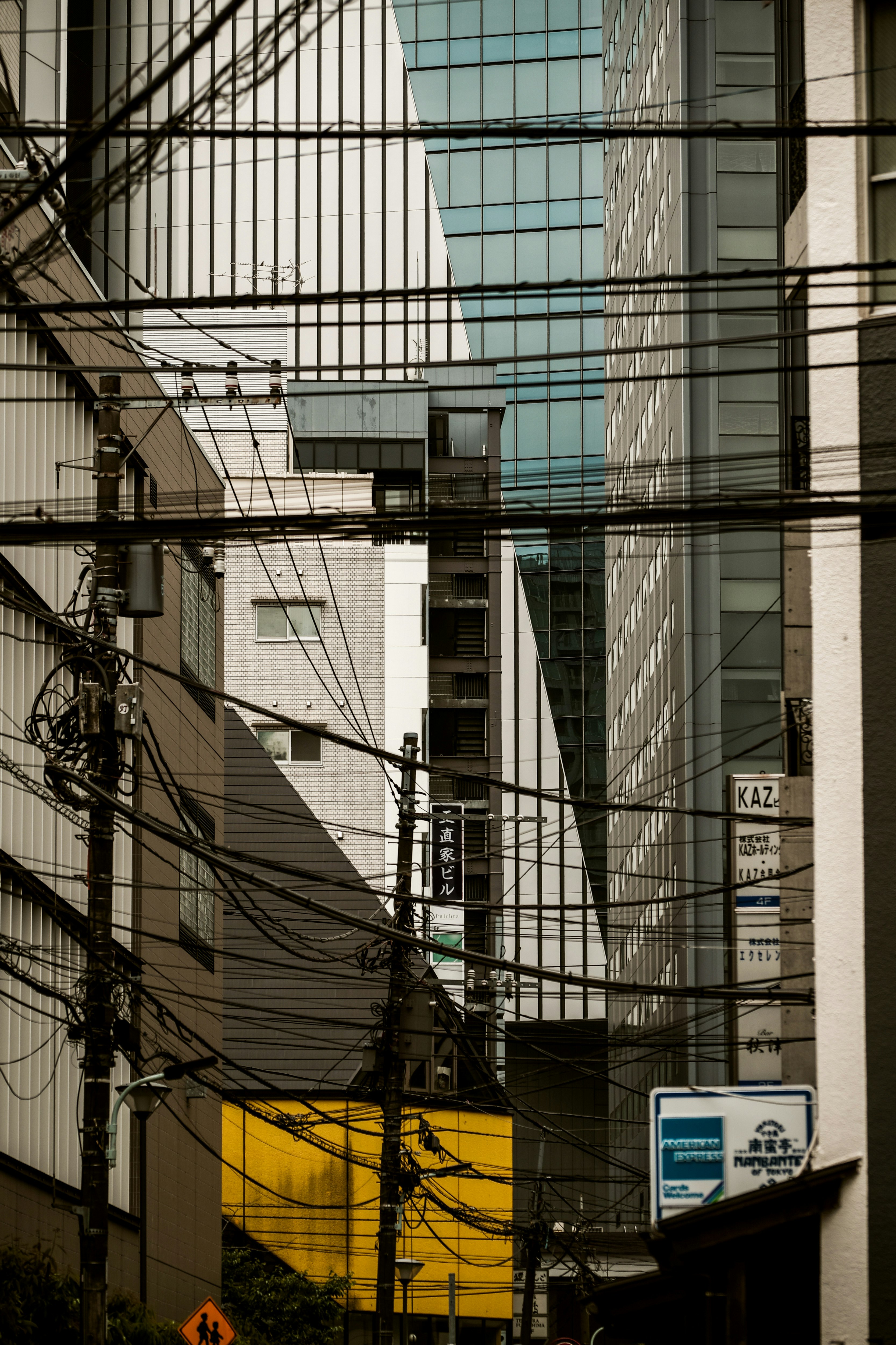 路地に張り巡らされた電線と高層ビルが見える都市の街並み