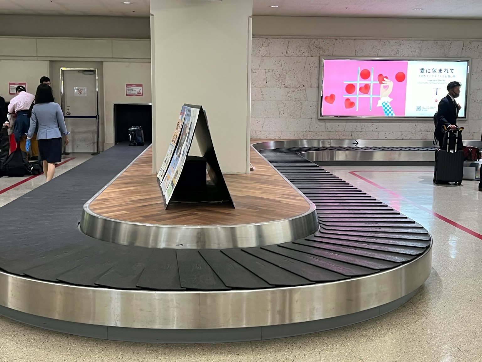 Zone de récupération des bagages de l'aéroport avec un tapis roulant circulaire et un panneau publicitaire
