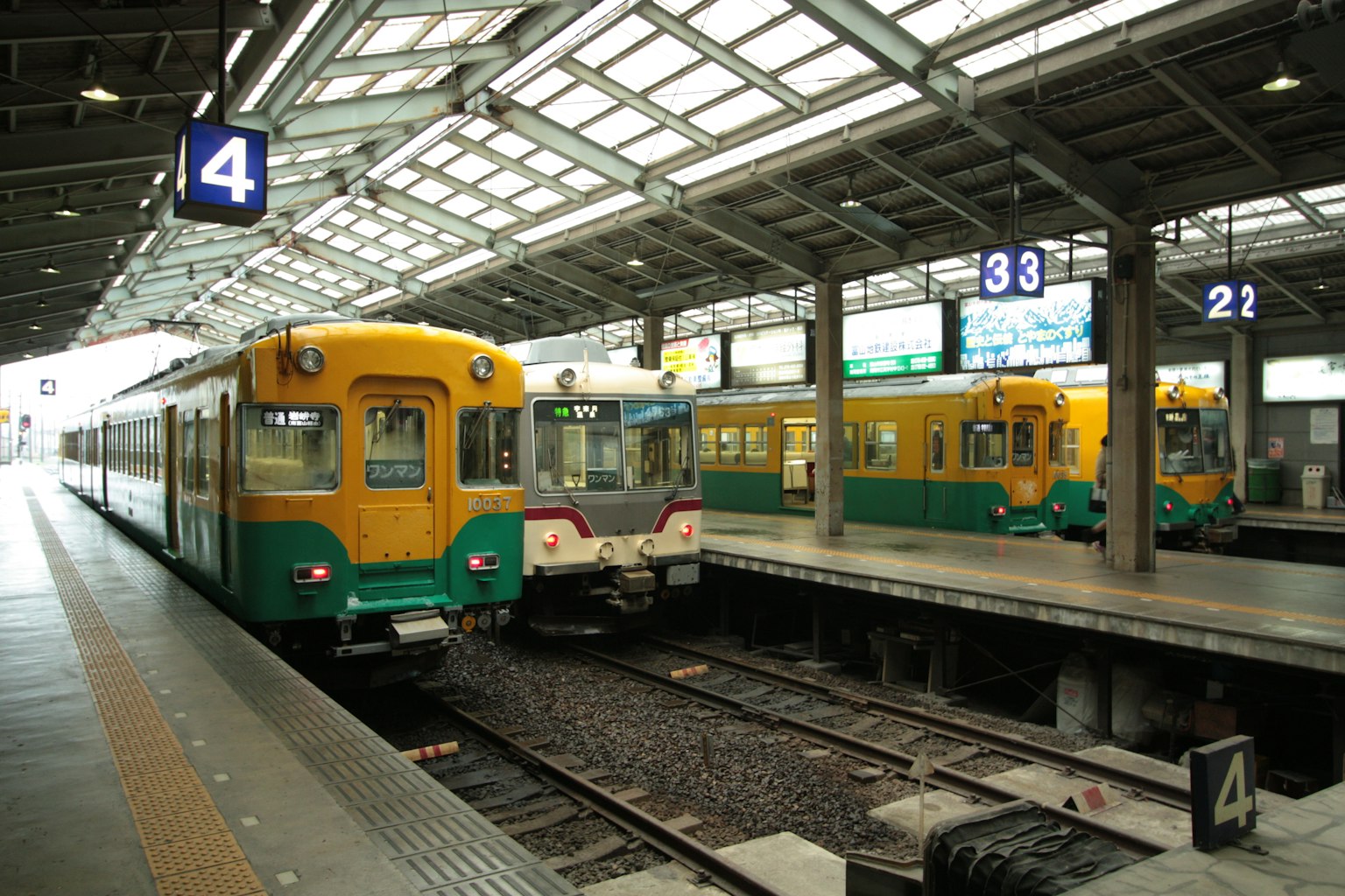 Kereta kuning dan hijau di platform stasiun dengan nomor platform 4 yang terlihat