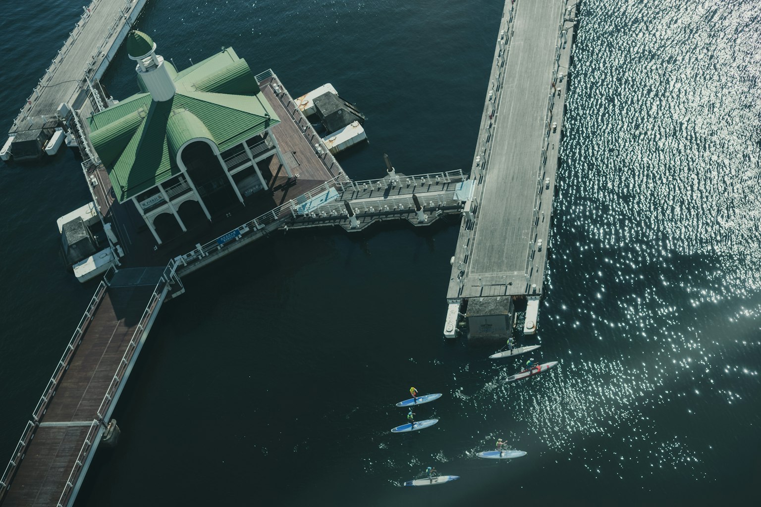 Vista aérea de un edificio con techo verde junto al agua con kayaks cercanos