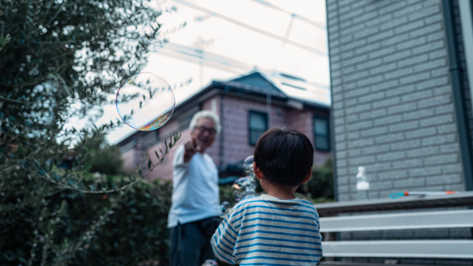 Un anciano saludando a un niño en un jardín