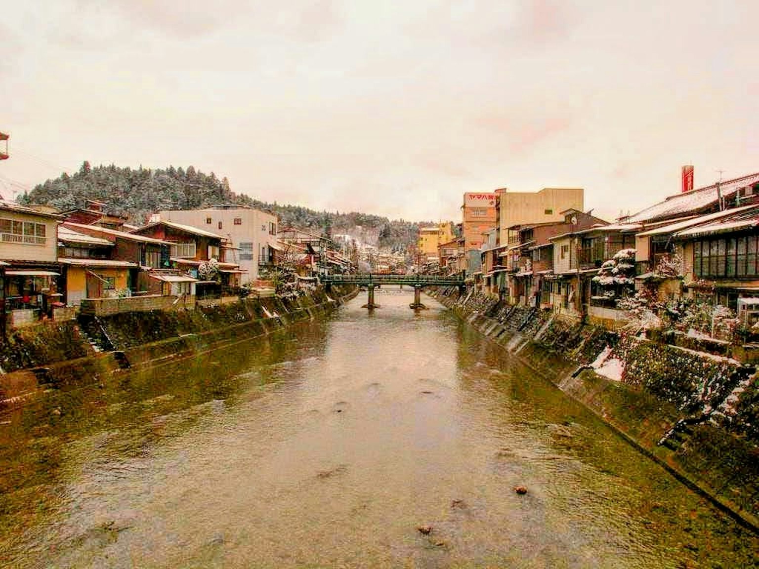 Vista panoramica di una città fluviale innevata con un ponte