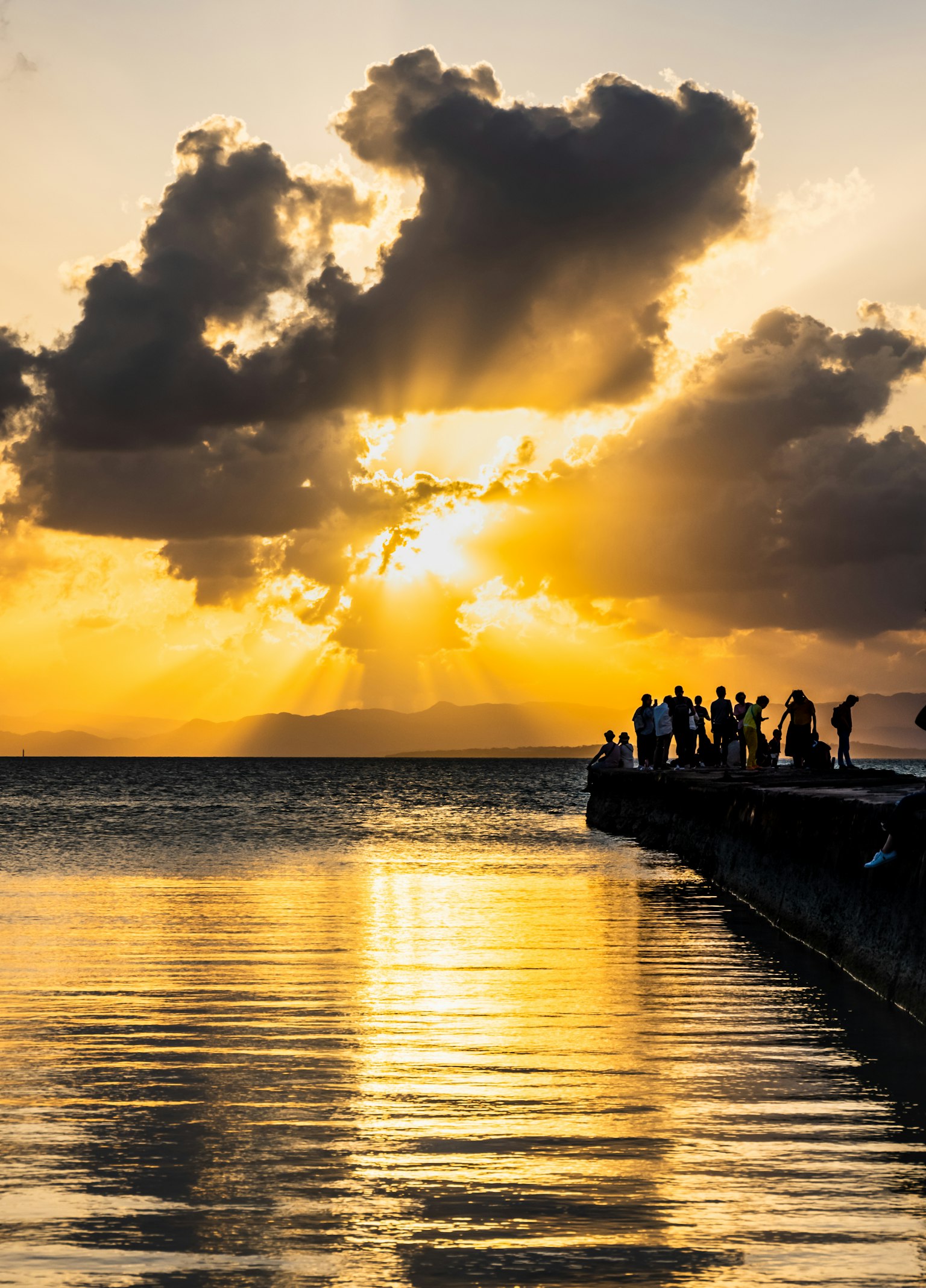 美丽的日落在水面上反射，码头上有人的轮廓