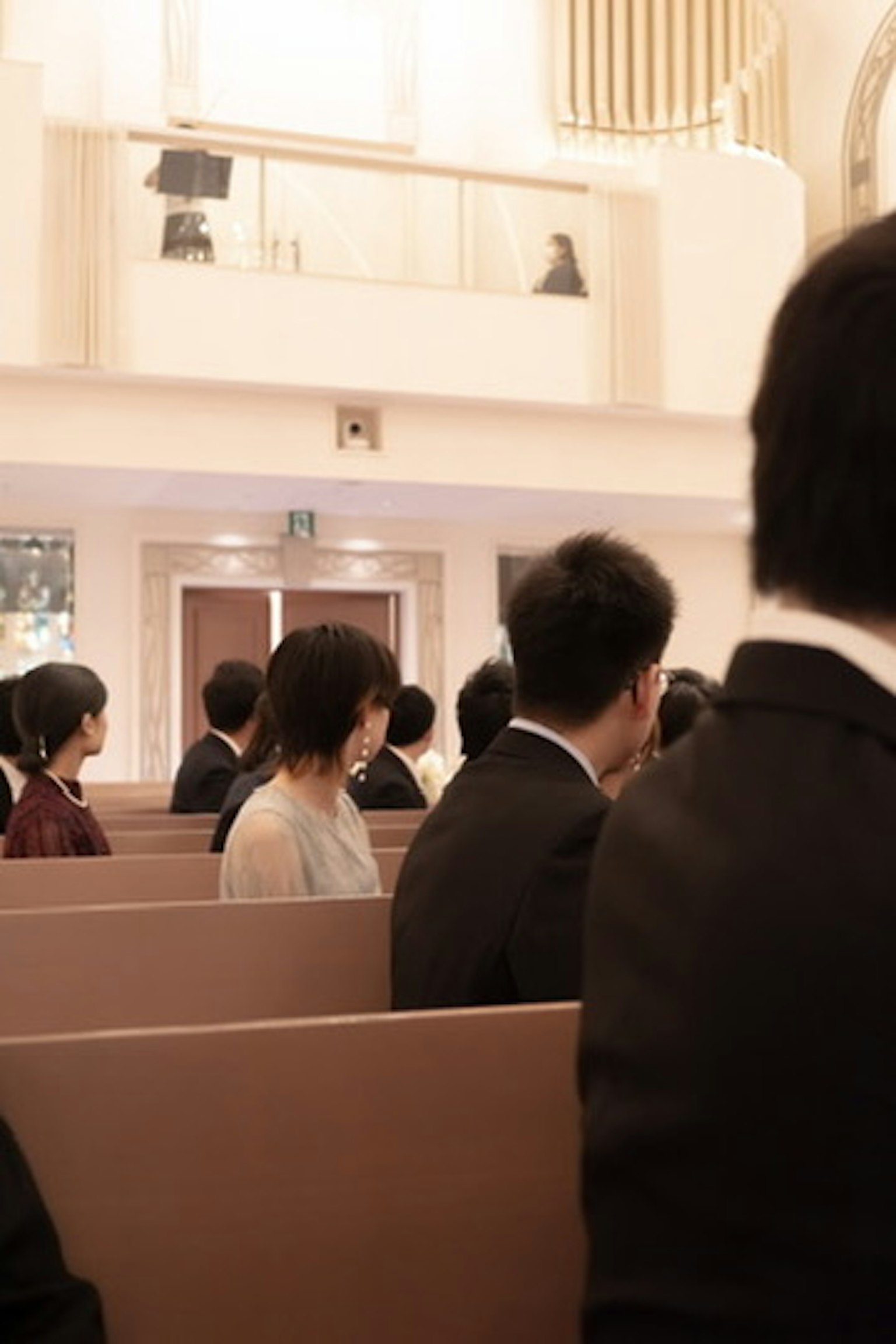 Personnes assises dans une église avec des vêtements de couleur douce et des costumes noirs