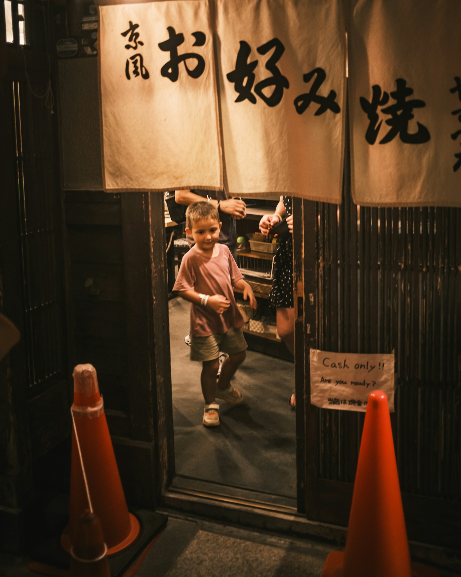 Ein kleines Kind tanzt am Eingang eines Izakaya mit einem fröhlichen Ausdruck
