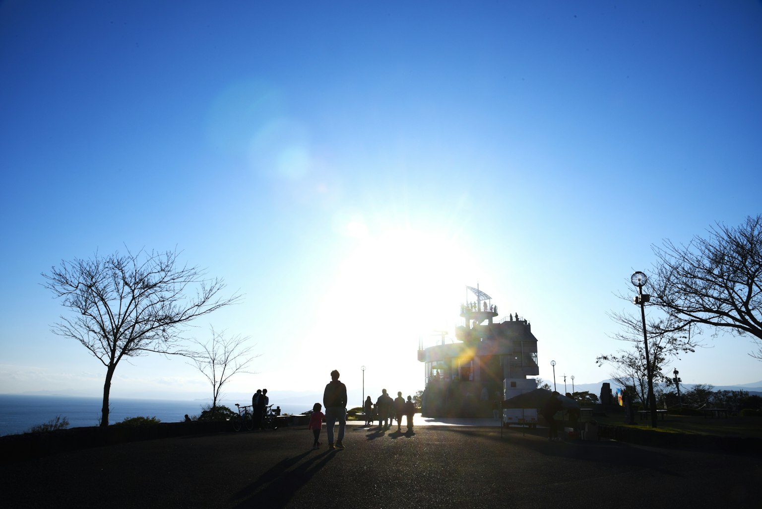 Silhouette di persone che camminano verso un luminoso tramonto con alberi sullo sfondo