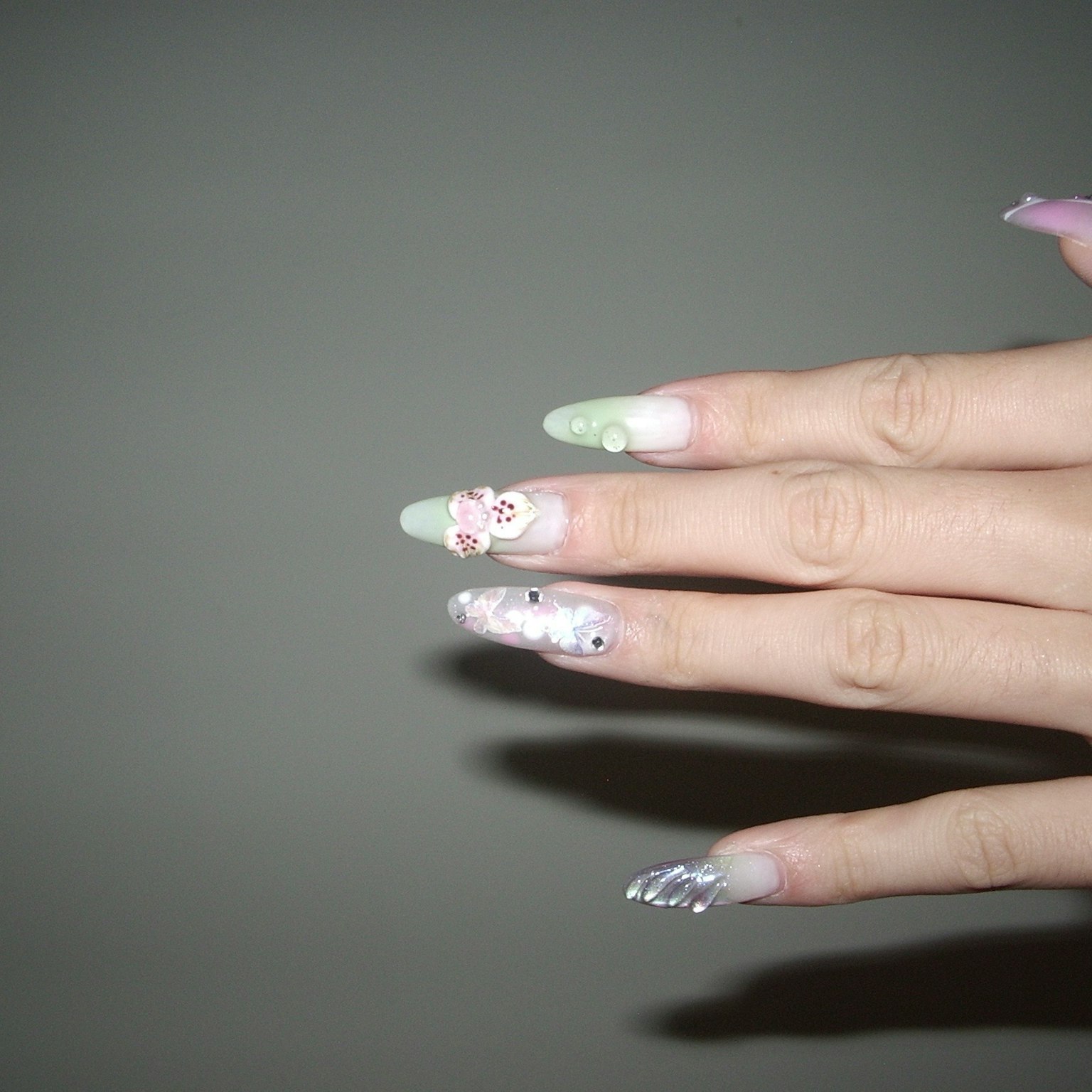 Hand with colorful nail art featuring floral designs and pastel colors