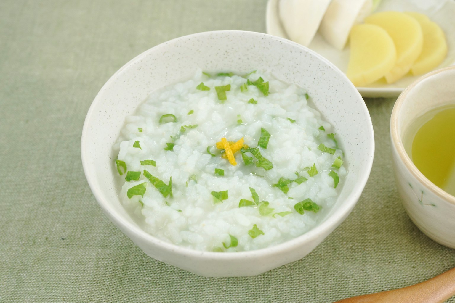Ciotola di porridge di riso guarnita con erbe verdi e zenzero affettato