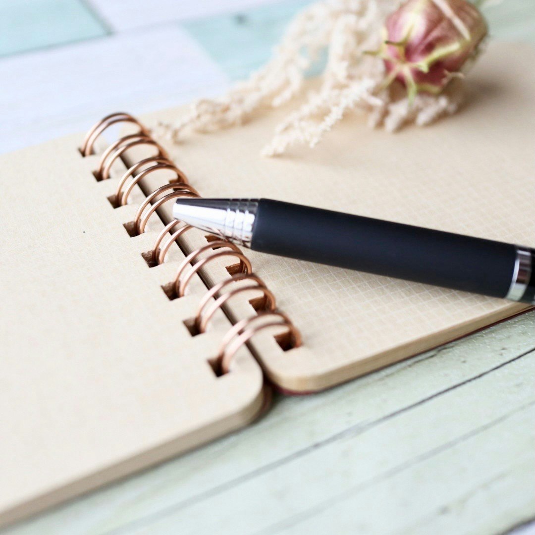 Nahaufnahme eines Notizbuchs mit einem schwarzen Stift und Spiralbindung