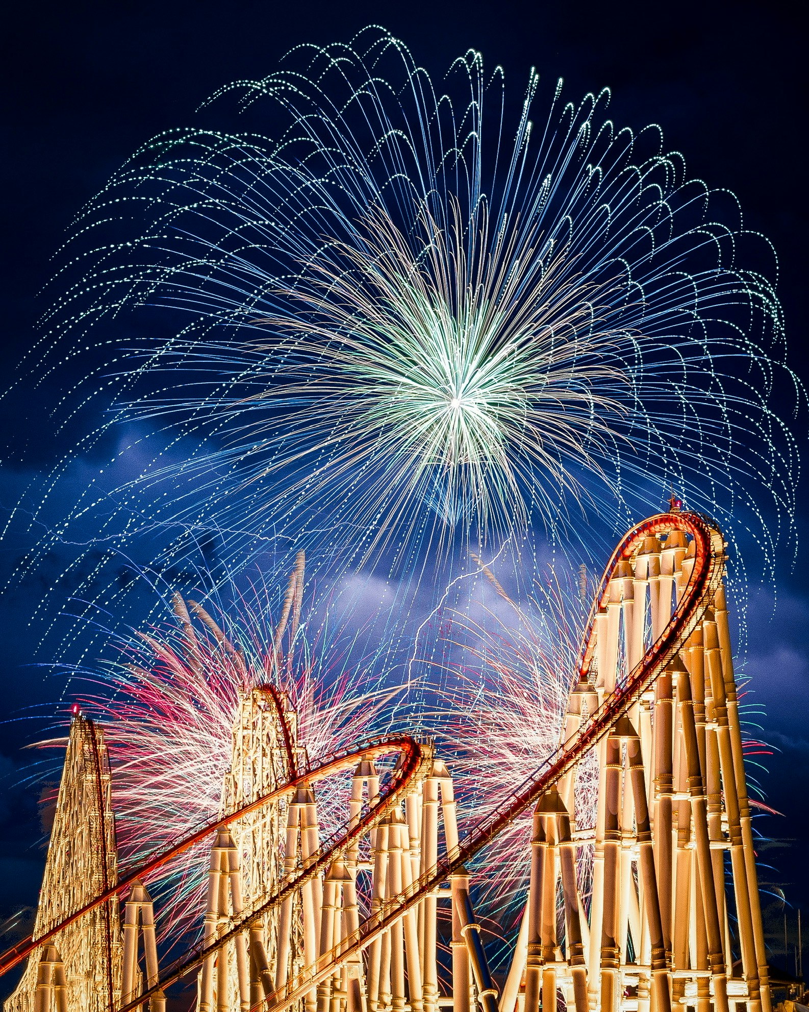 fireworks over rows of bamboo tubes at a festival night
