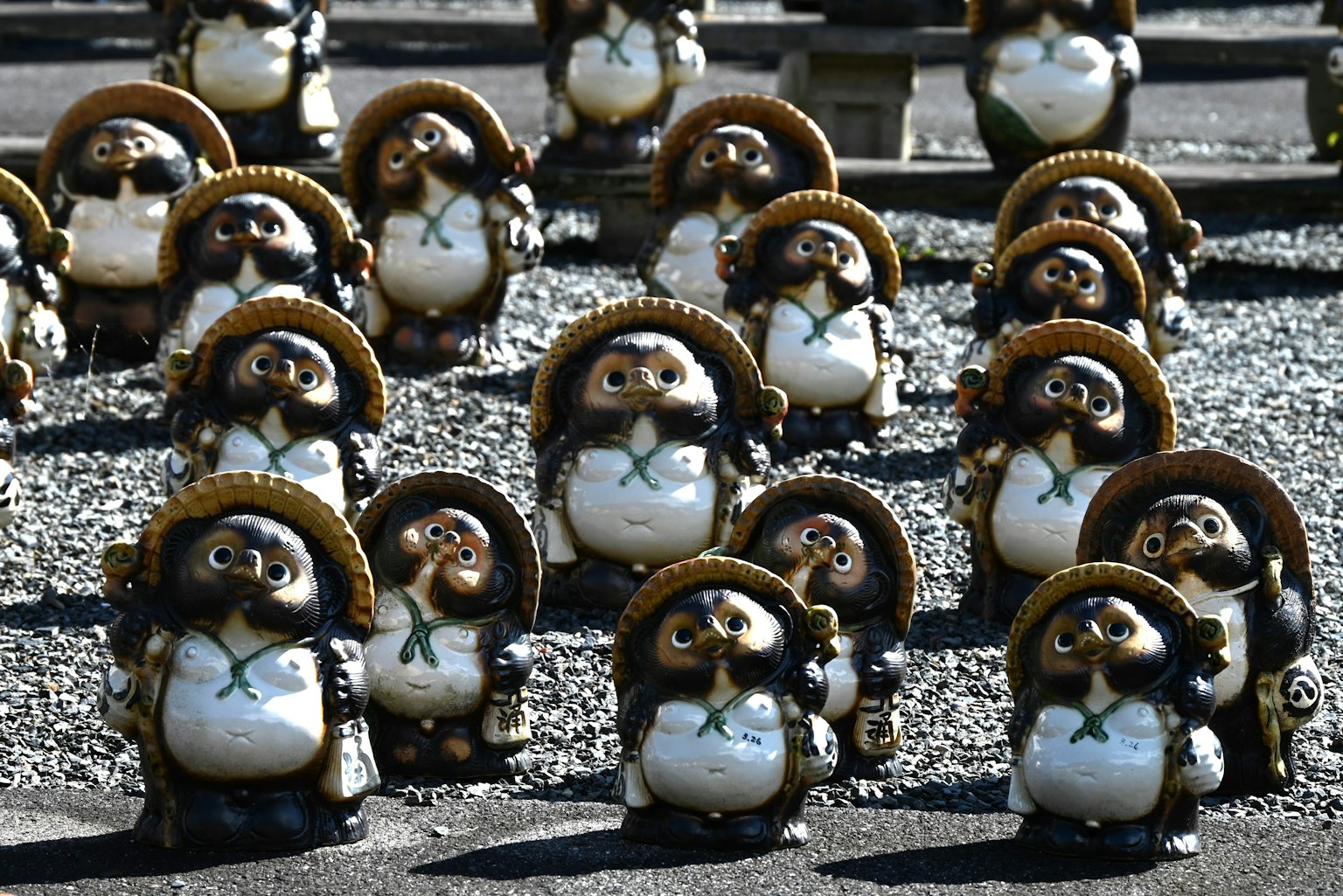 Una colección de figuras de tanuki de cerámica dispuestas en un jardín