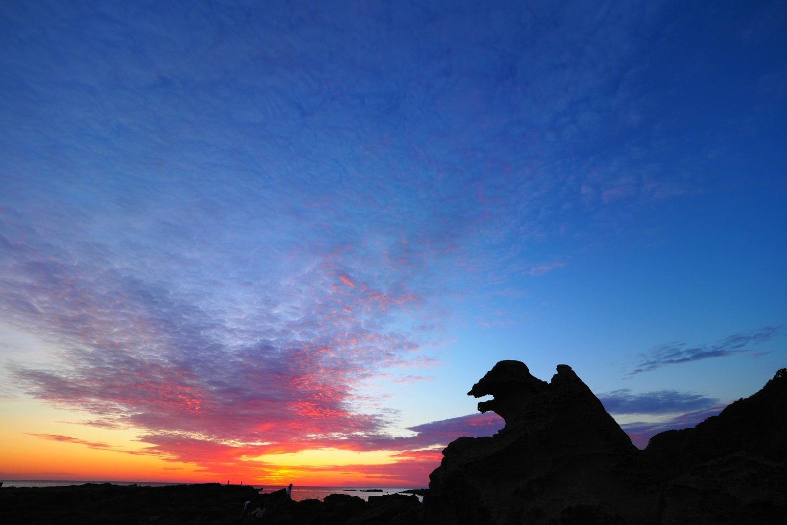 Silhouette di rocce contro un cielo di tramonto vibrante