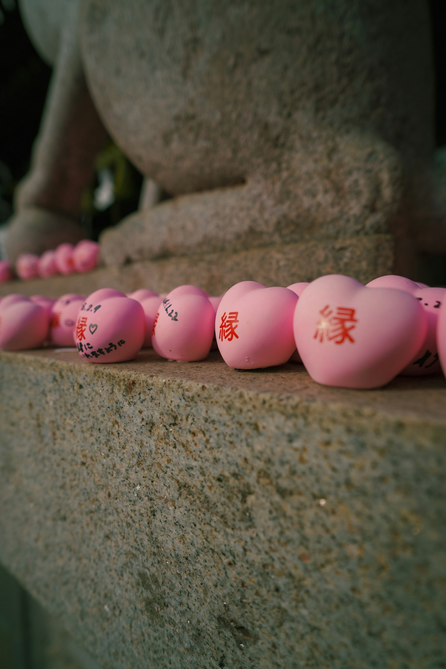 A row of pink heart-shaped objects on a stone ledge