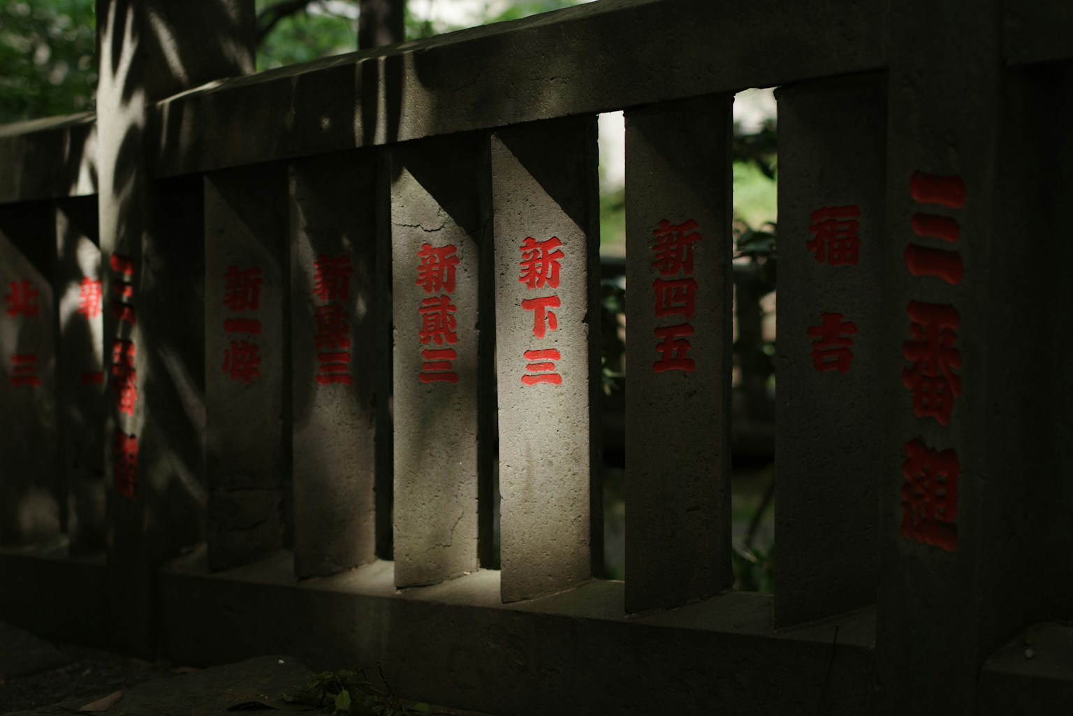 Close-up of a stone railing with red inscriptions illuminated by natural light
