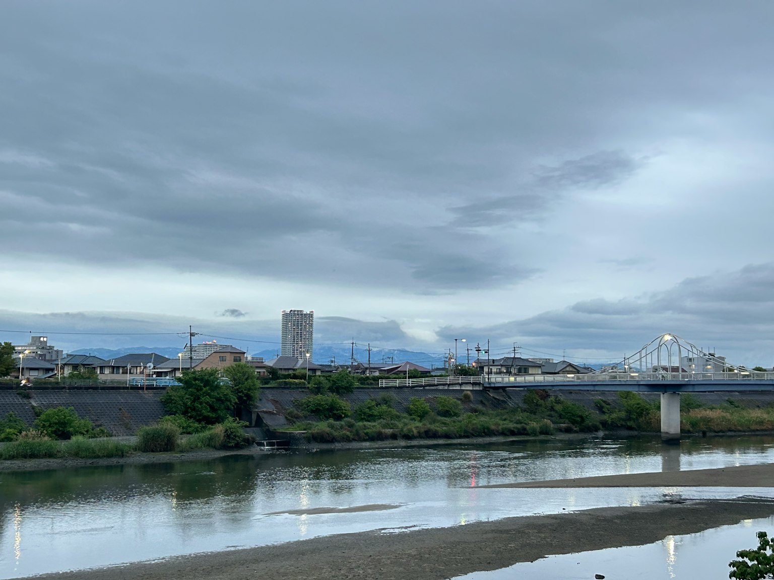 Un paesaggio con un fiume e lo skyline di una città sotto un cielo nuvoloso