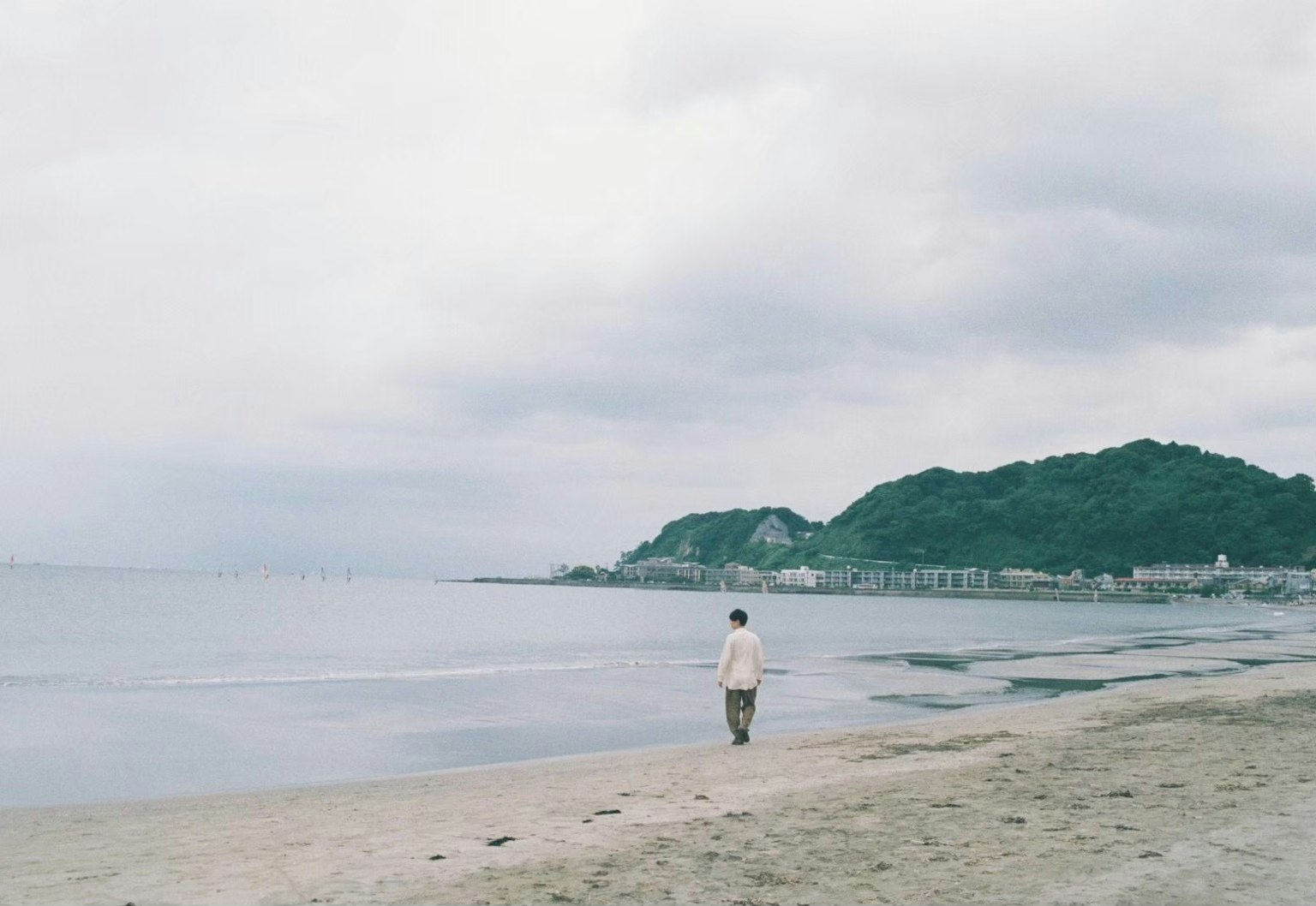 一個人在陰雲密布的天空下走在安靜的海灘上