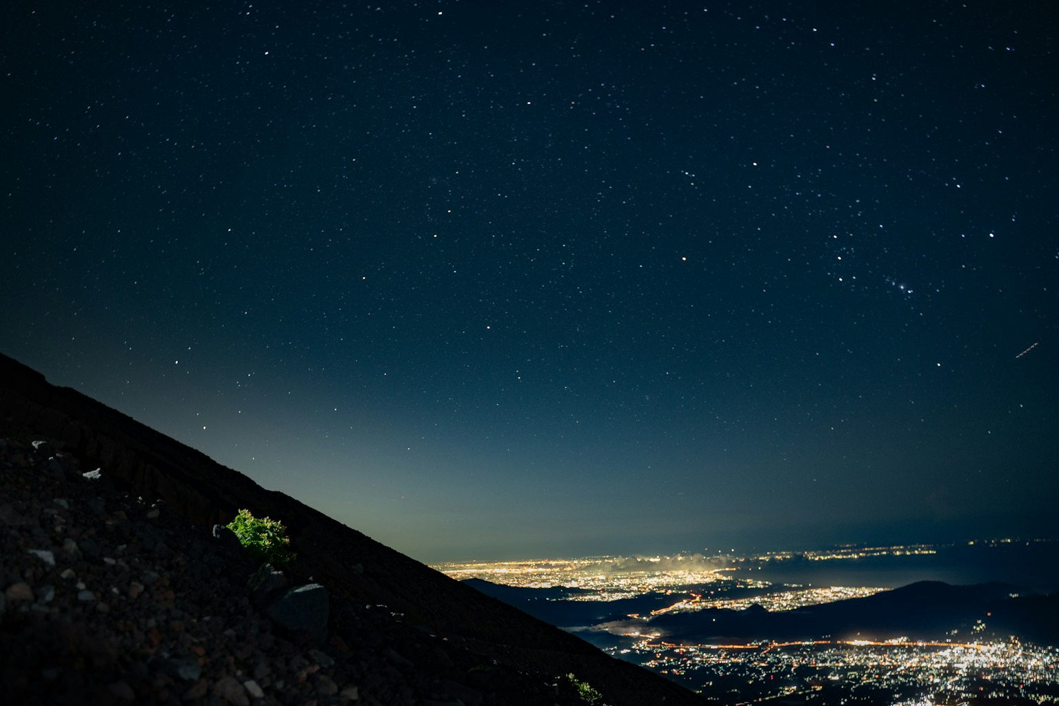 Starry sky over a cityscape viewed from a mountain slope