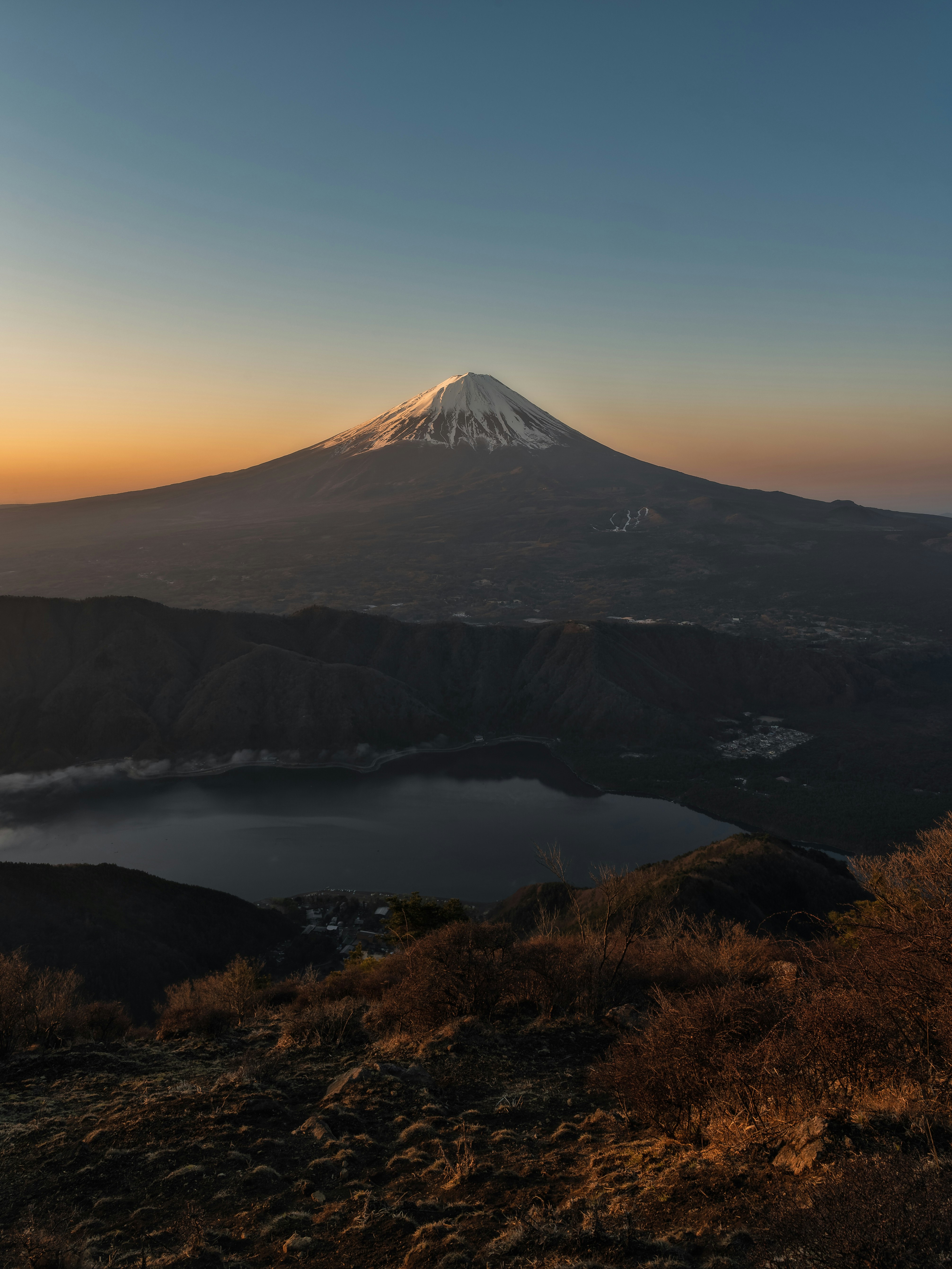 lago al atardecer con la silueta de una montaña a lo lejos