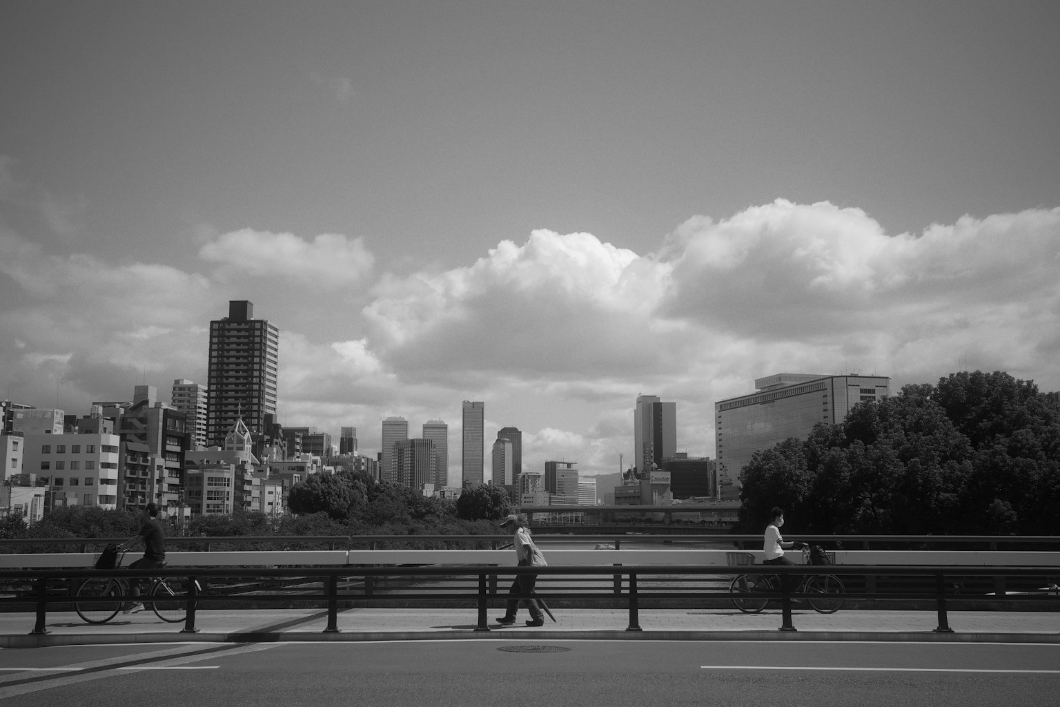Black and white urban landscape with people walking and clouds in the sky