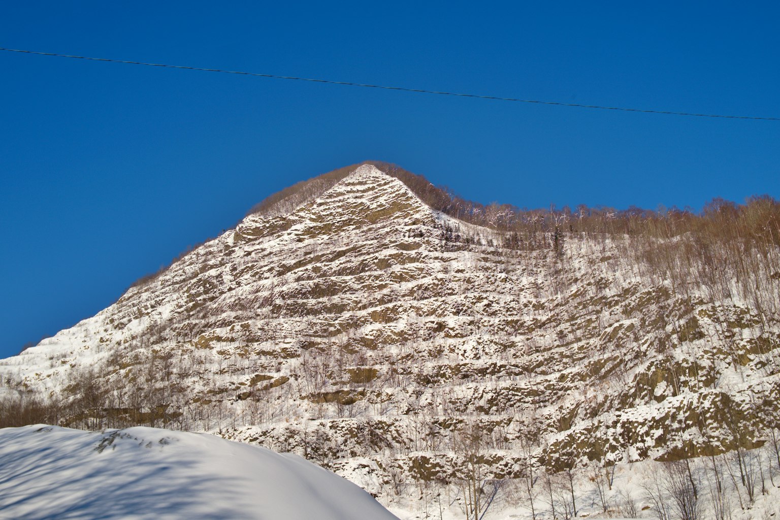Pendio di montagna coperto di neve con cielo blu chiaro