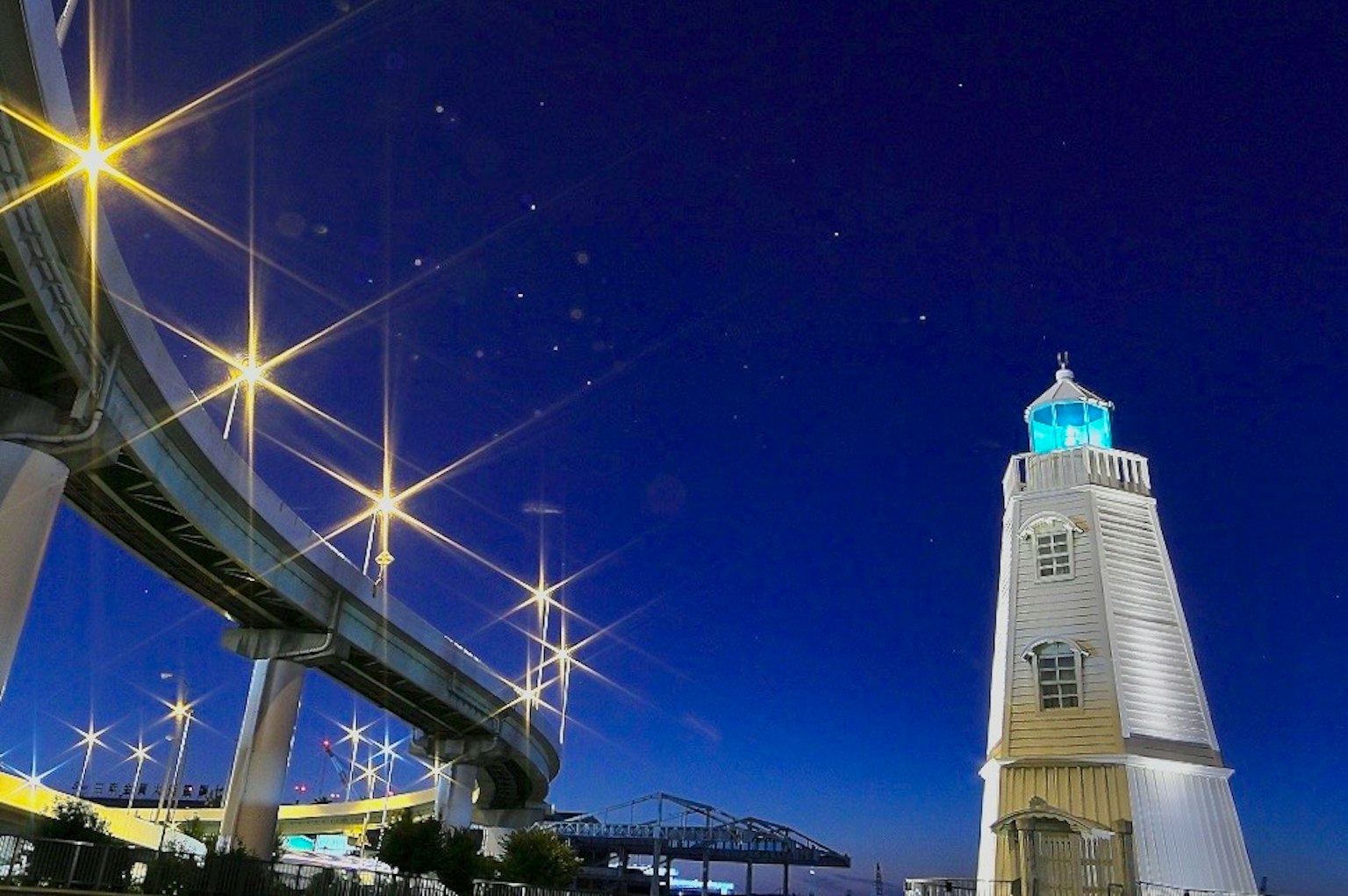 Schöne Aussicht auf einen Leuchtturm und eine Brücke, die nachts mit funkelnden Sternen beleuchtet sind