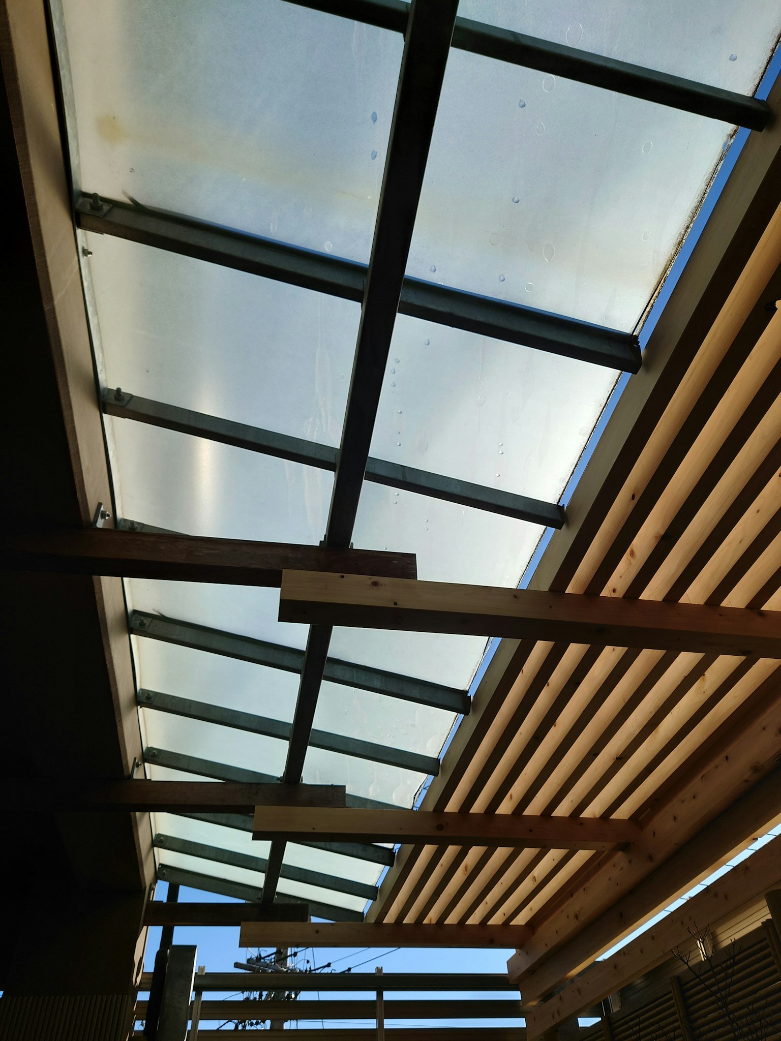 Blick von unten auf eine Decke aus Holz und Glasplatten