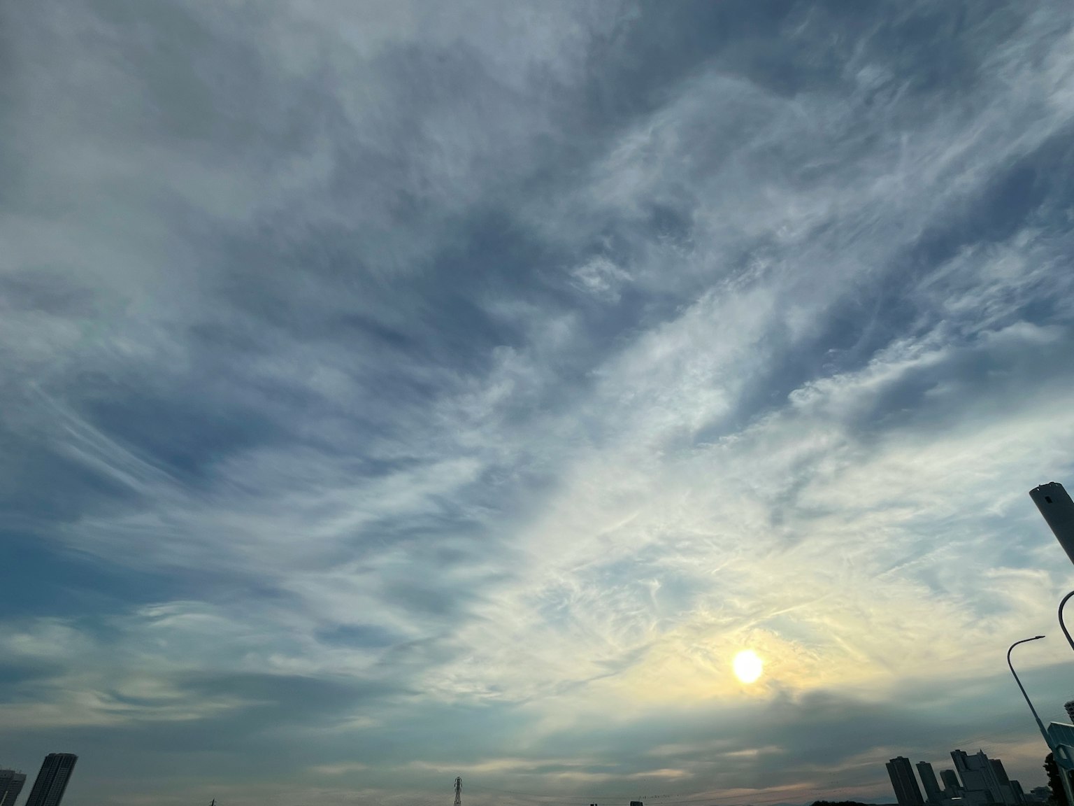 A scenic view of a blue sky with wispy white clouds at sunset