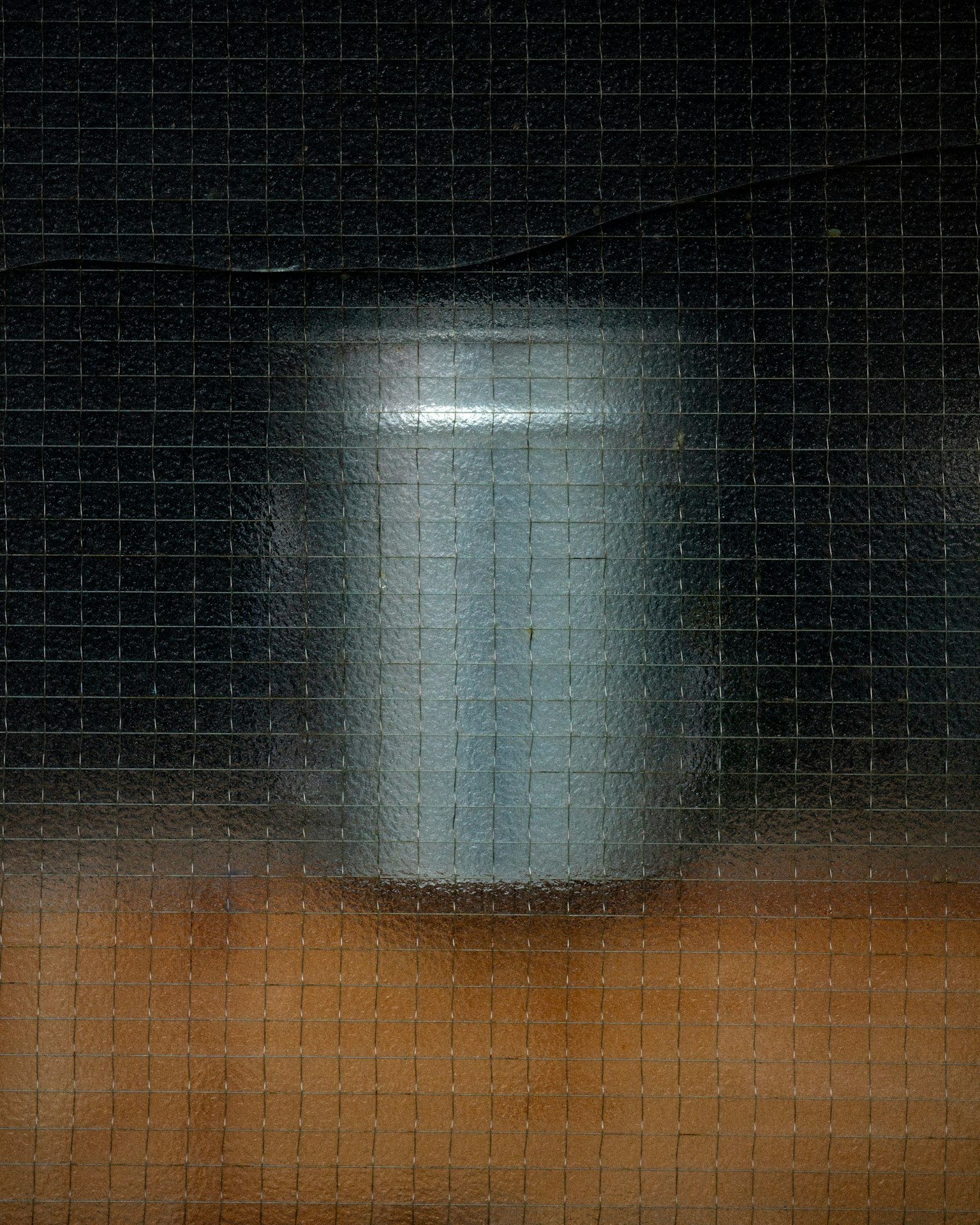 ぼやけた銀色の缶が網目越しに見える