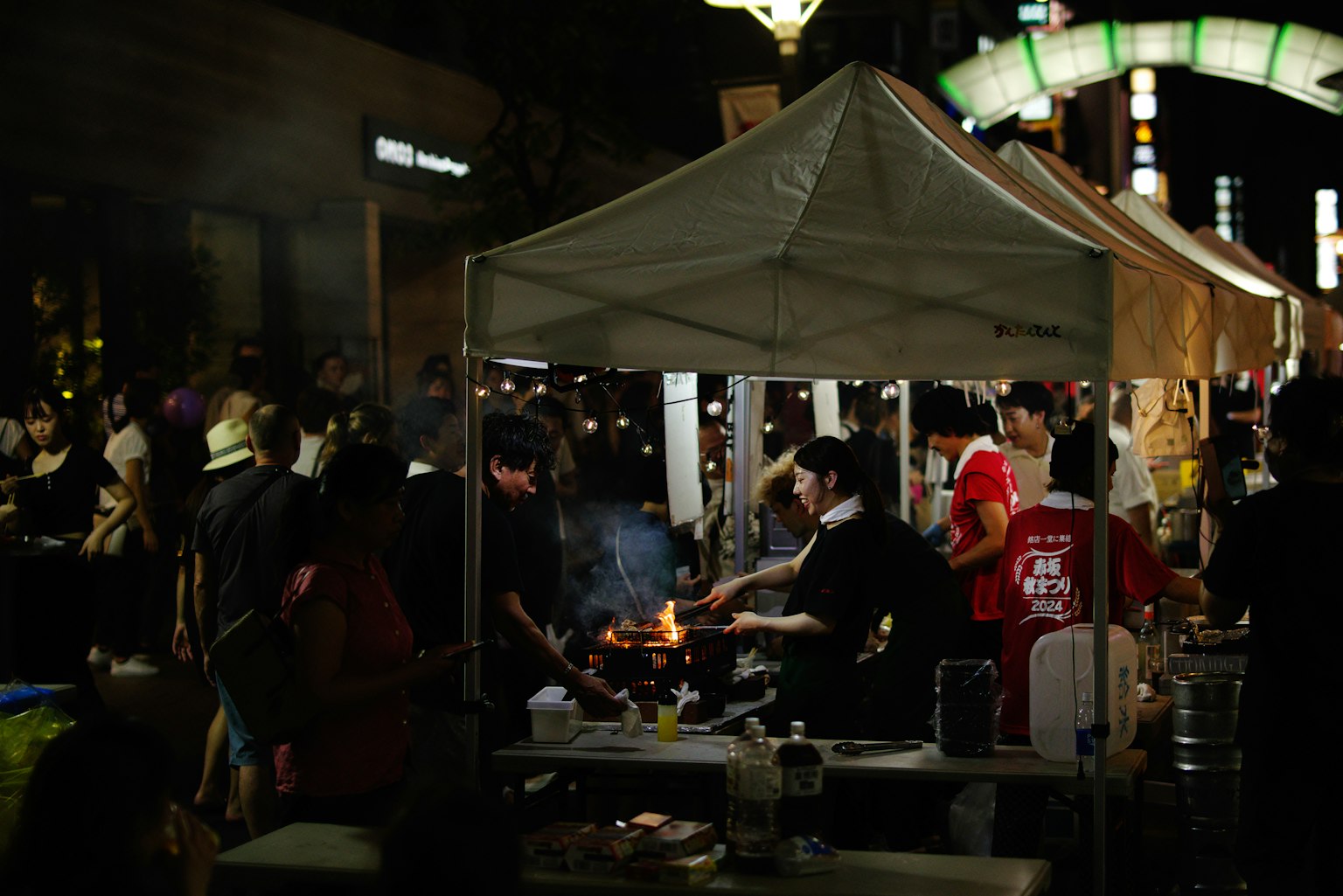 Orang-orang memasak di pasar malam dengan kerumunan yang ramai