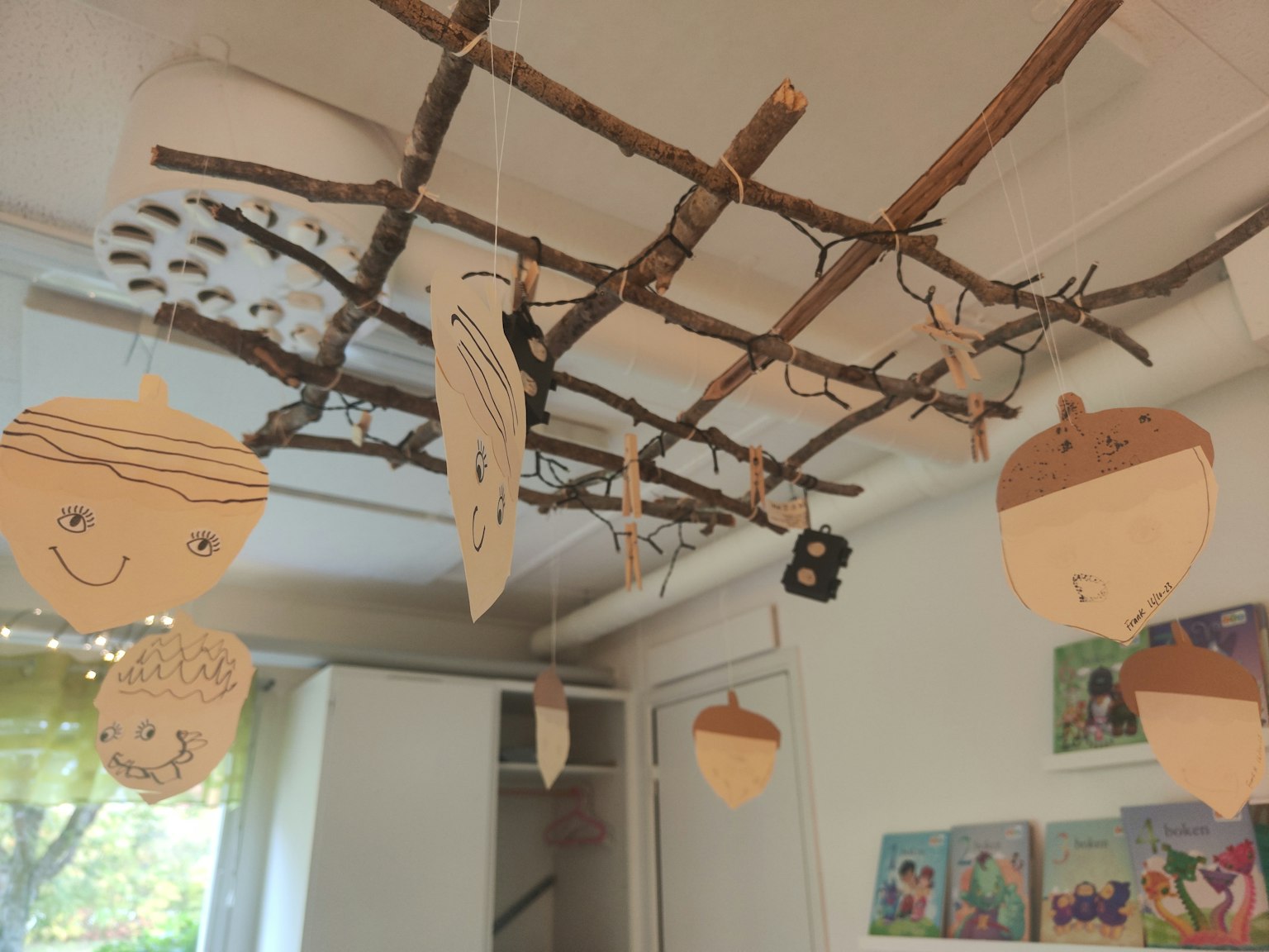 Vista interior de una habitación con decoraciones hechas a mano colgando de una rama