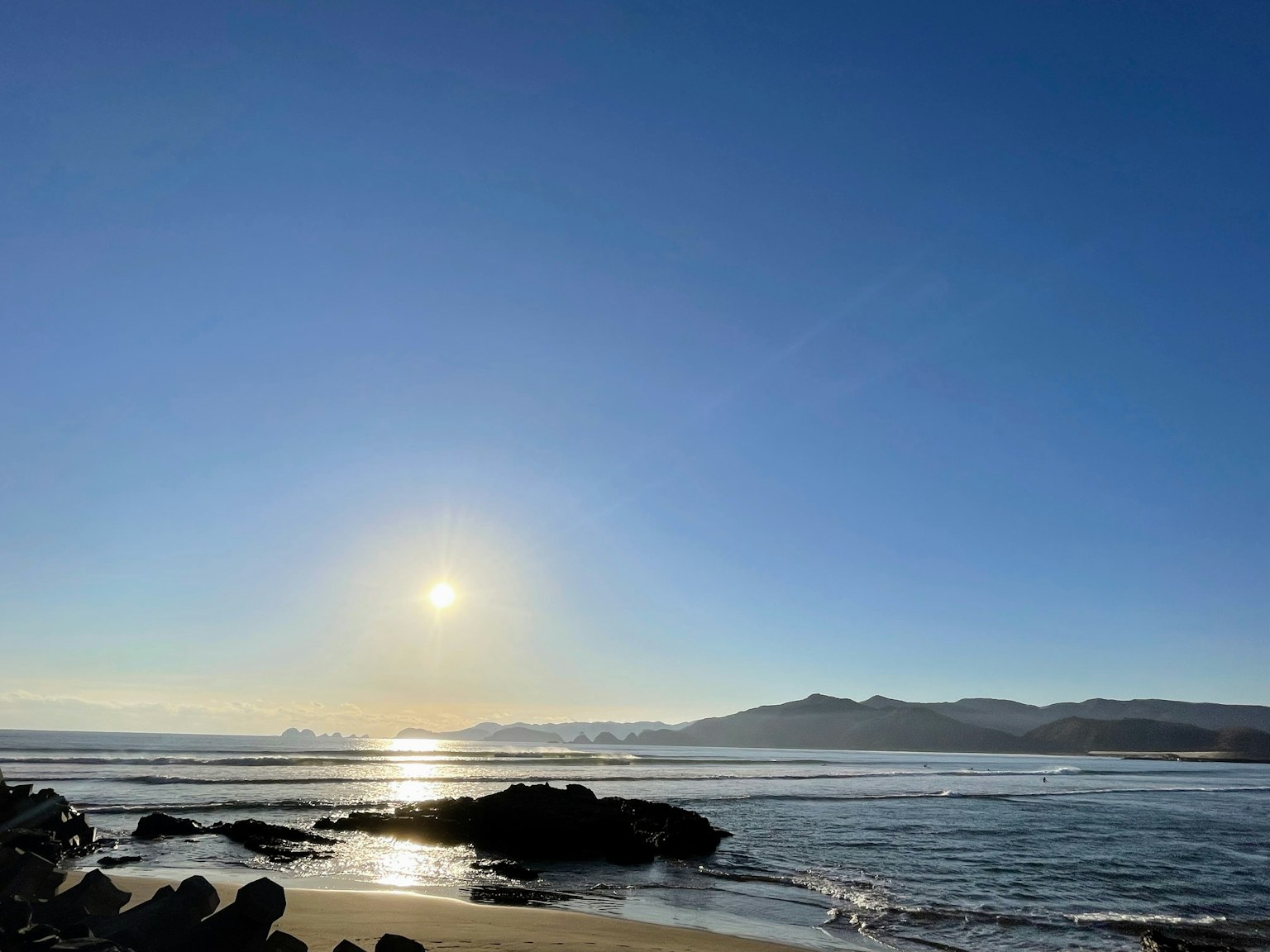 Vista panoramica del sole che tramonta sull'oceano calmo e il cielo blu chiaro