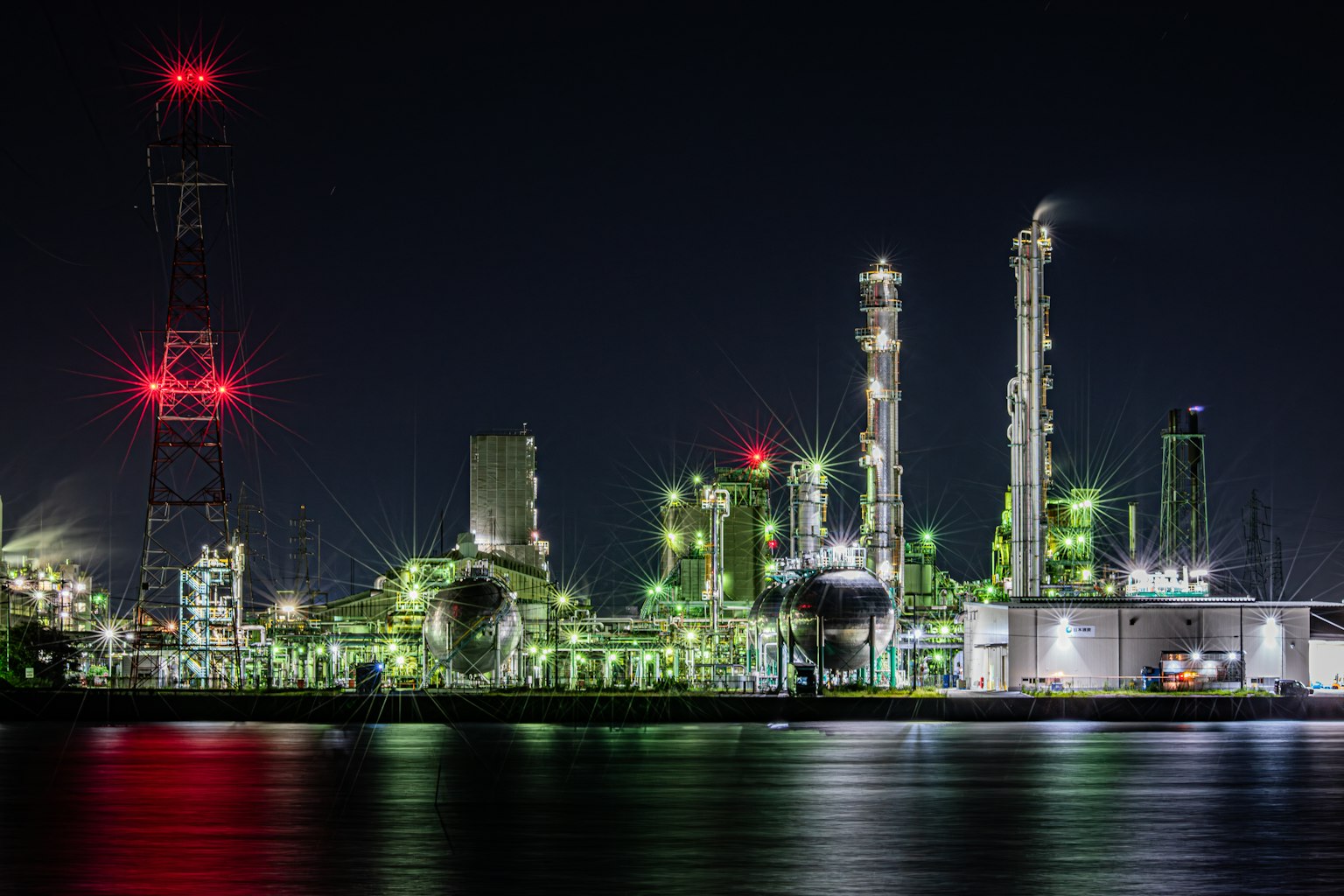 Industrielle Anlage mit grünen Lichtern bei Nacht