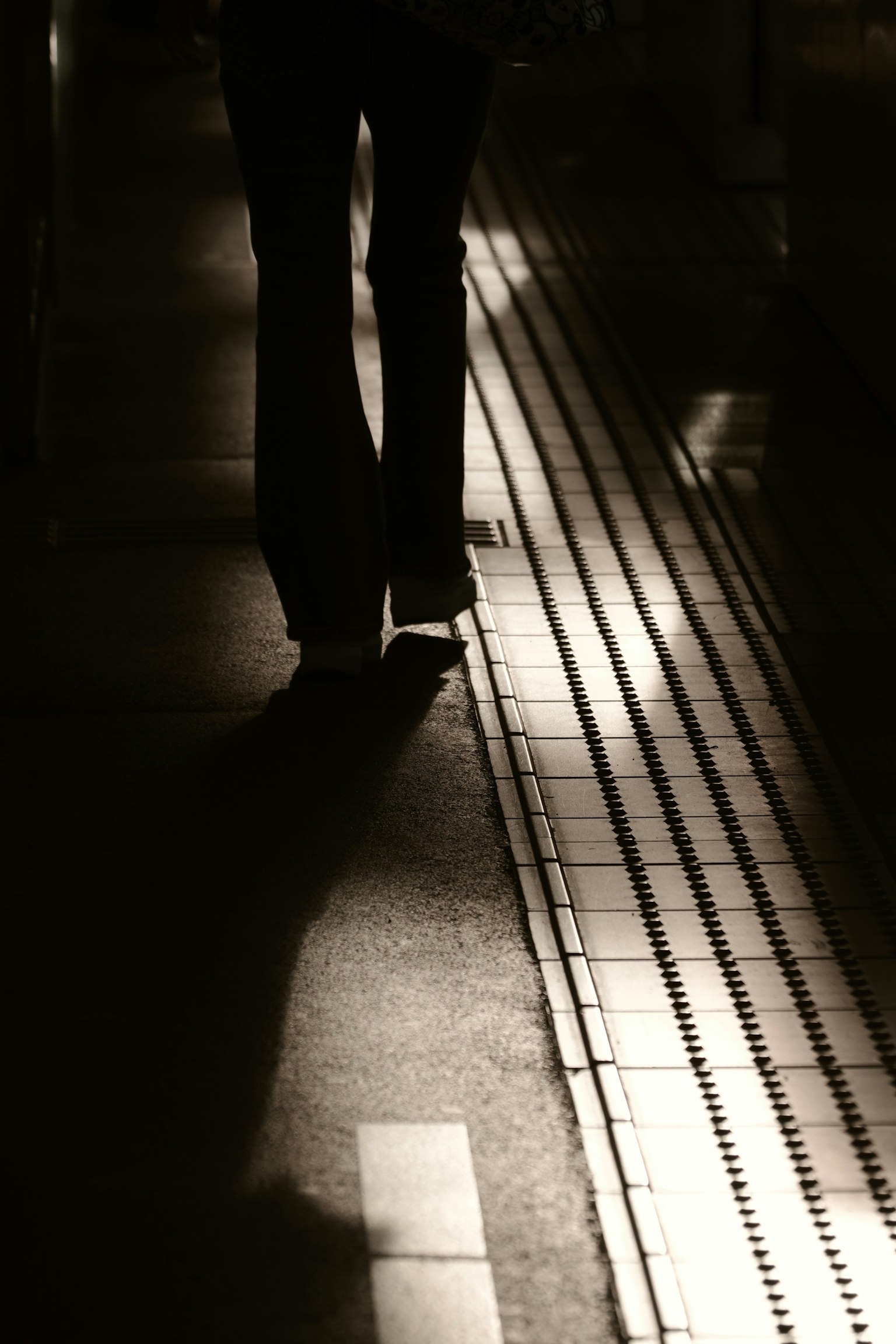Silhouette einer Person, die auf einer dunklen Bahnsteig geht