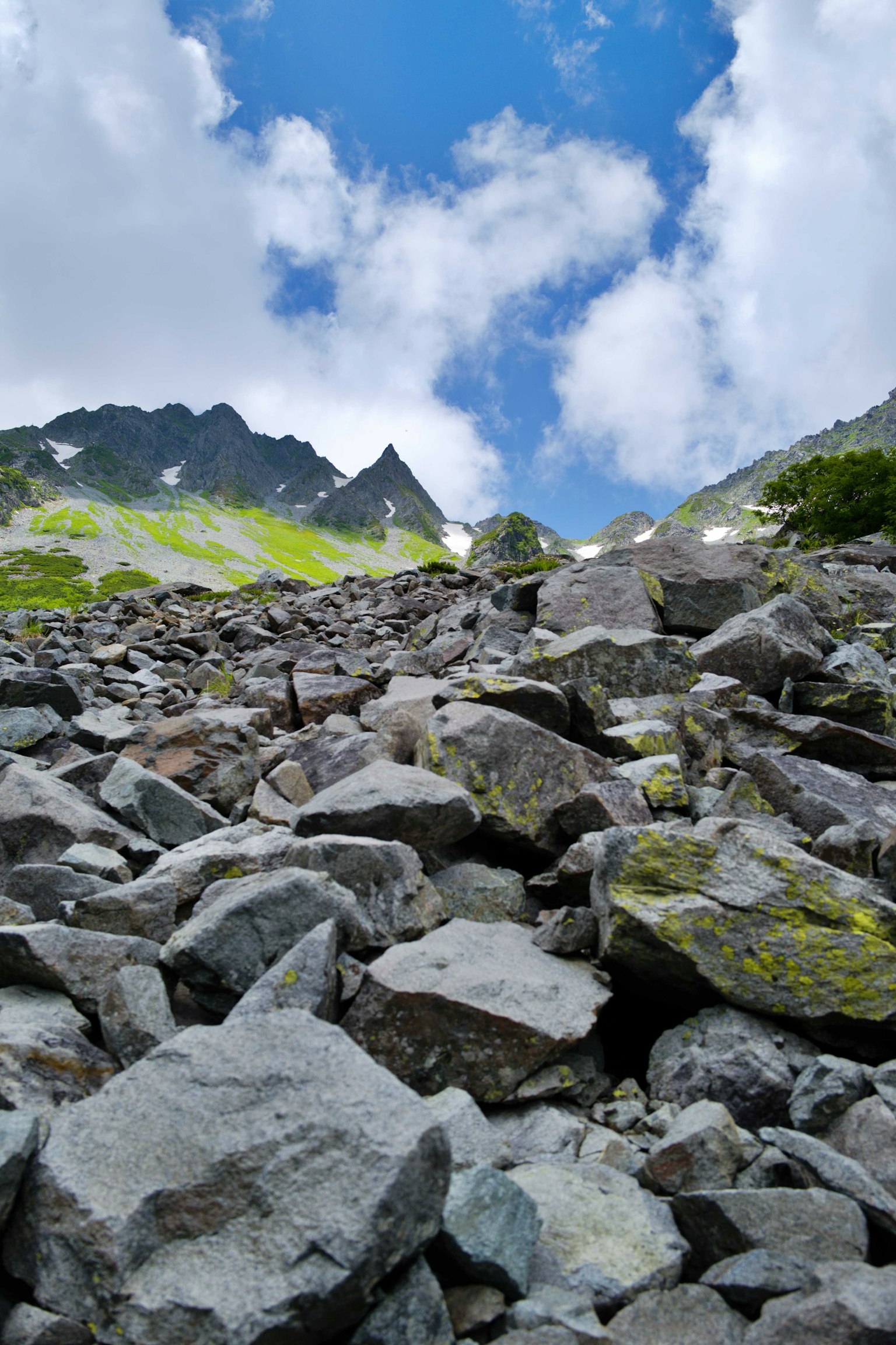 Pente rocheuse menant aux montagnes sous un ciel bleu