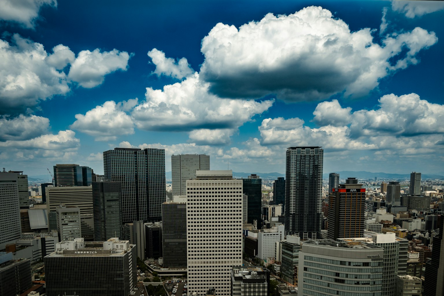 Horizonte de la ciudad con edificios altos bajo un cielo azul lleno de nubes blancas esponjosas