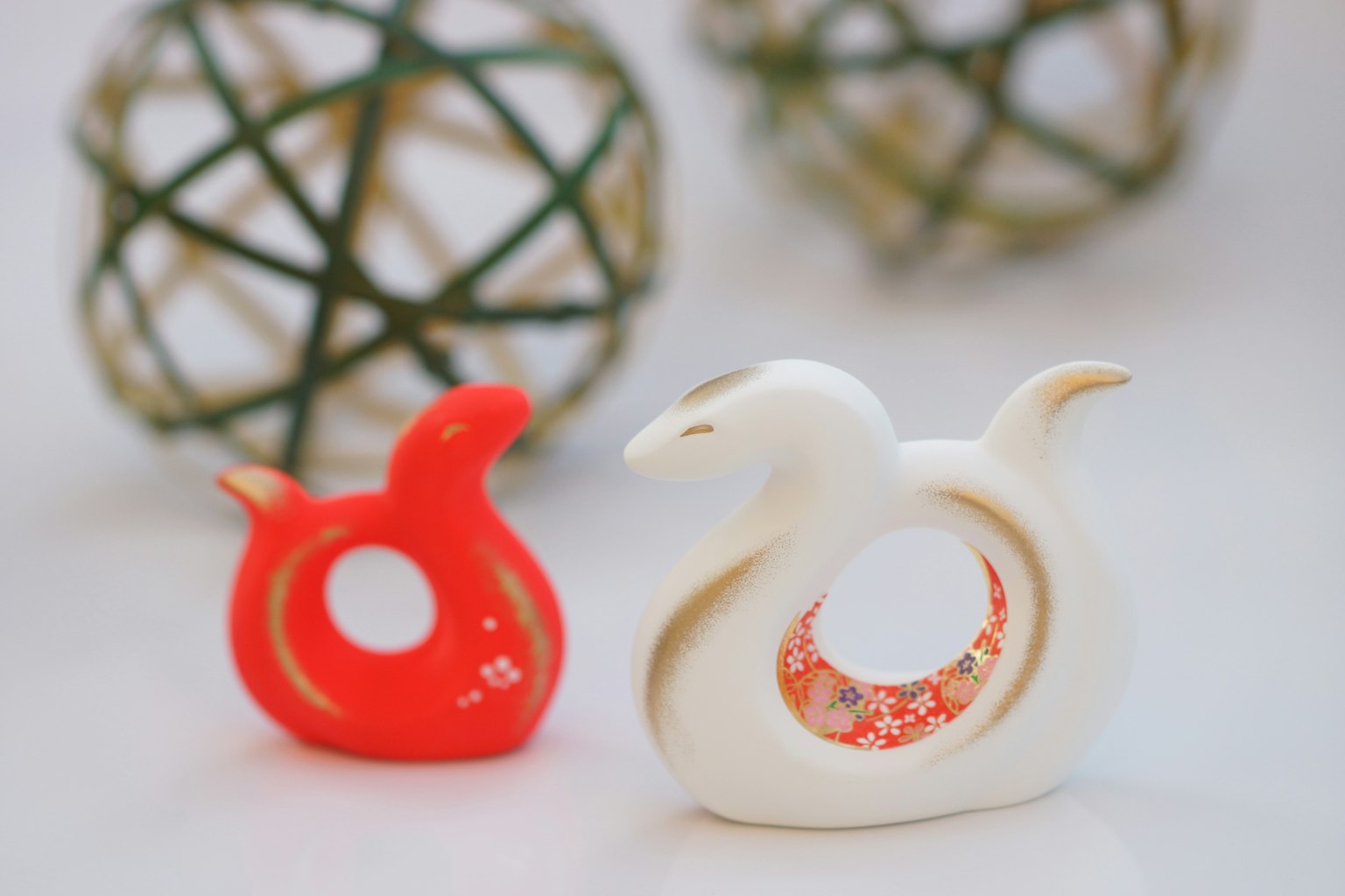 Figuritas de pájaros rojos y blancos con esferas decorativas al fondo