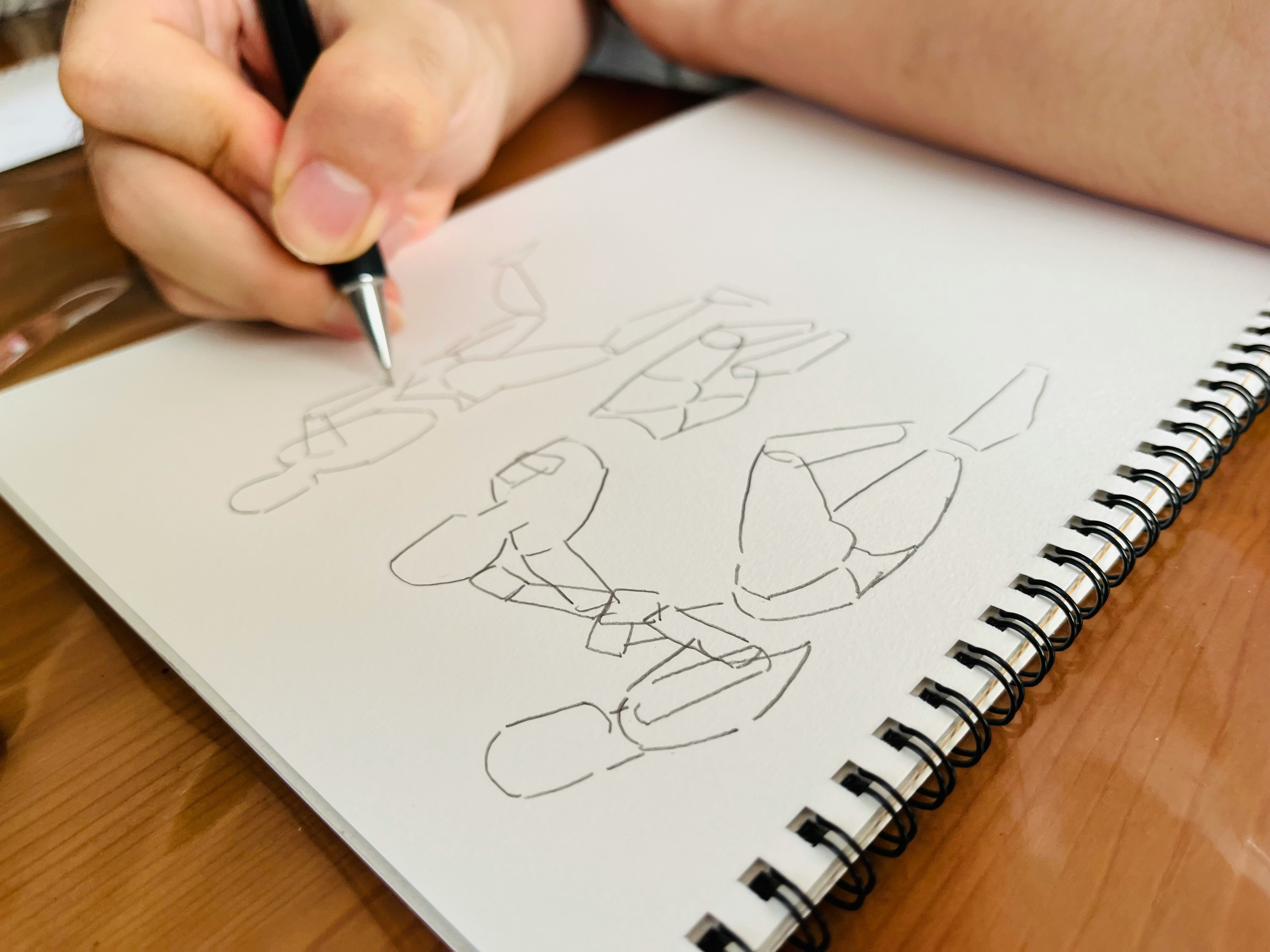 机の上でスケッチブックに描く手元